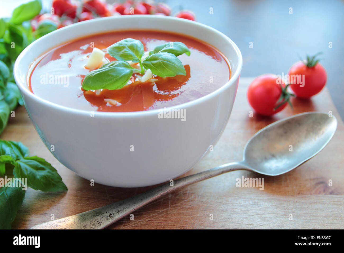Soupe de tomate savoureuse dans un bol blanc avec des feuilles de basilic Banque D'Images