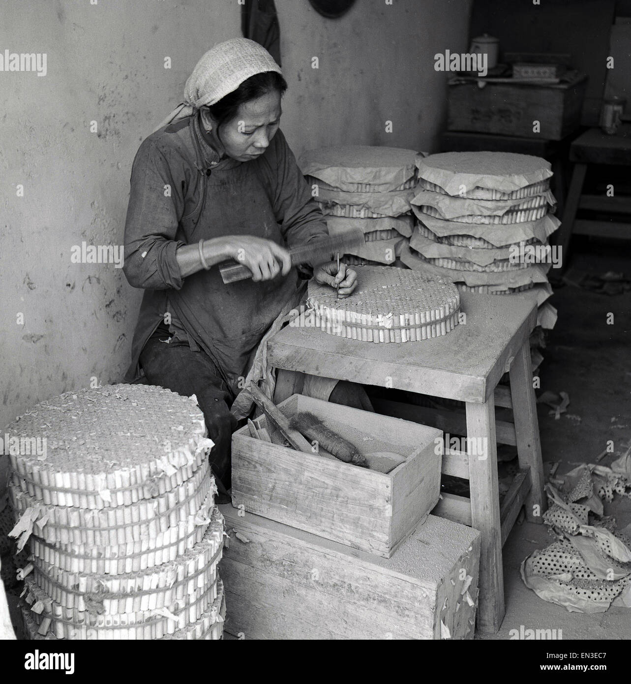 Historique des années 1950, Hong Kong, travailleuse d'artifice faisant à la main. Elle est de mettre des trous dans le papier pour la poudre d'entrer dans. Banque D'Images