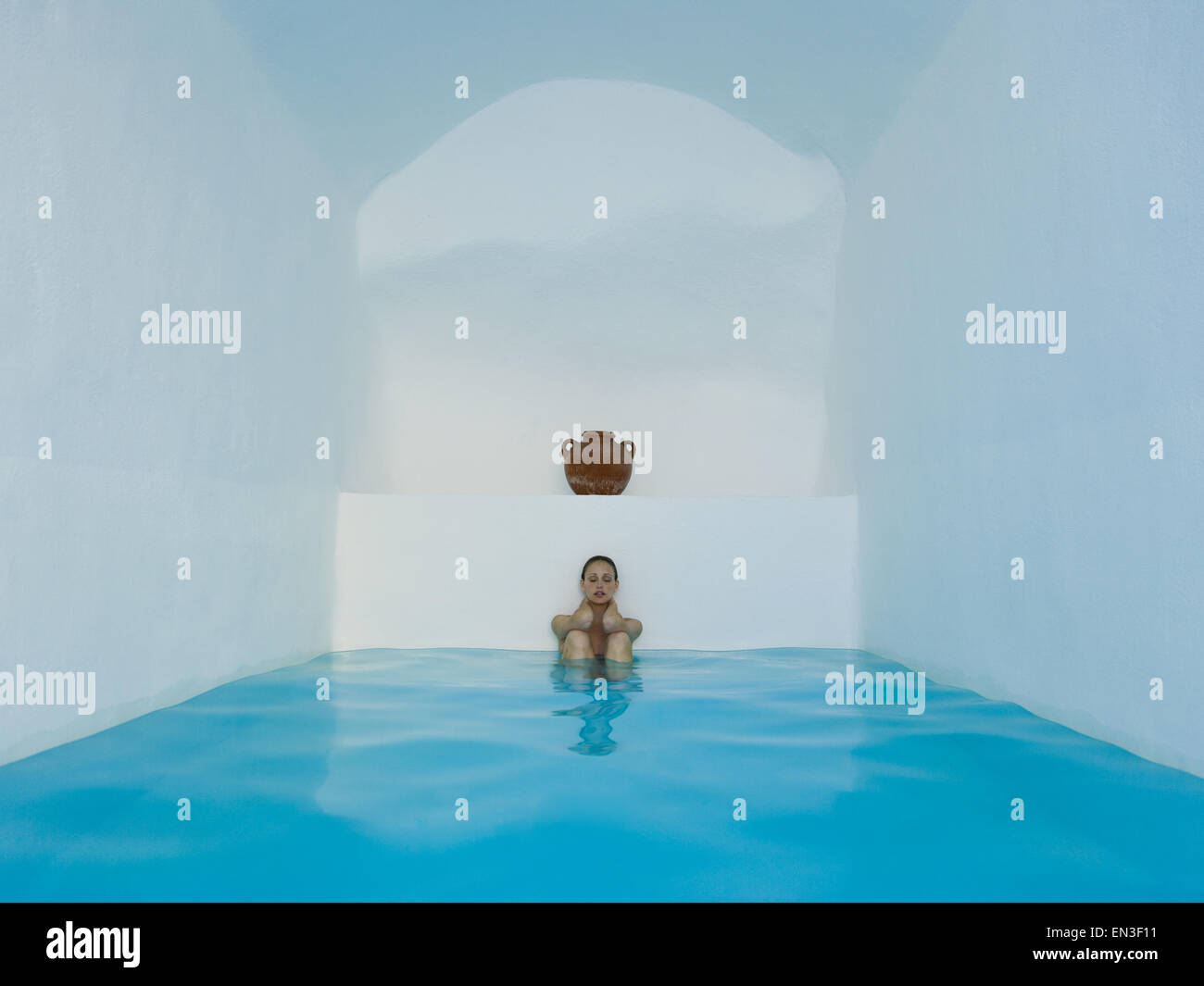 Femme assise dans le bassin, les genoux jusqu'à l'urne d'argile Banque D'Images