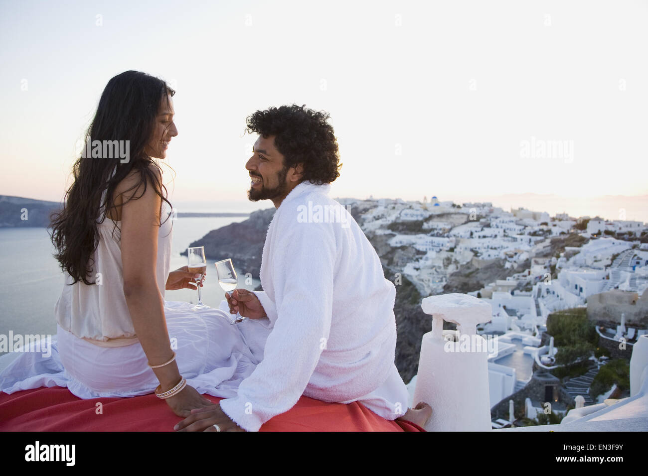 Couple assis en plein air avec des flûtes à champagne et scenic background smiling Banque D'Images