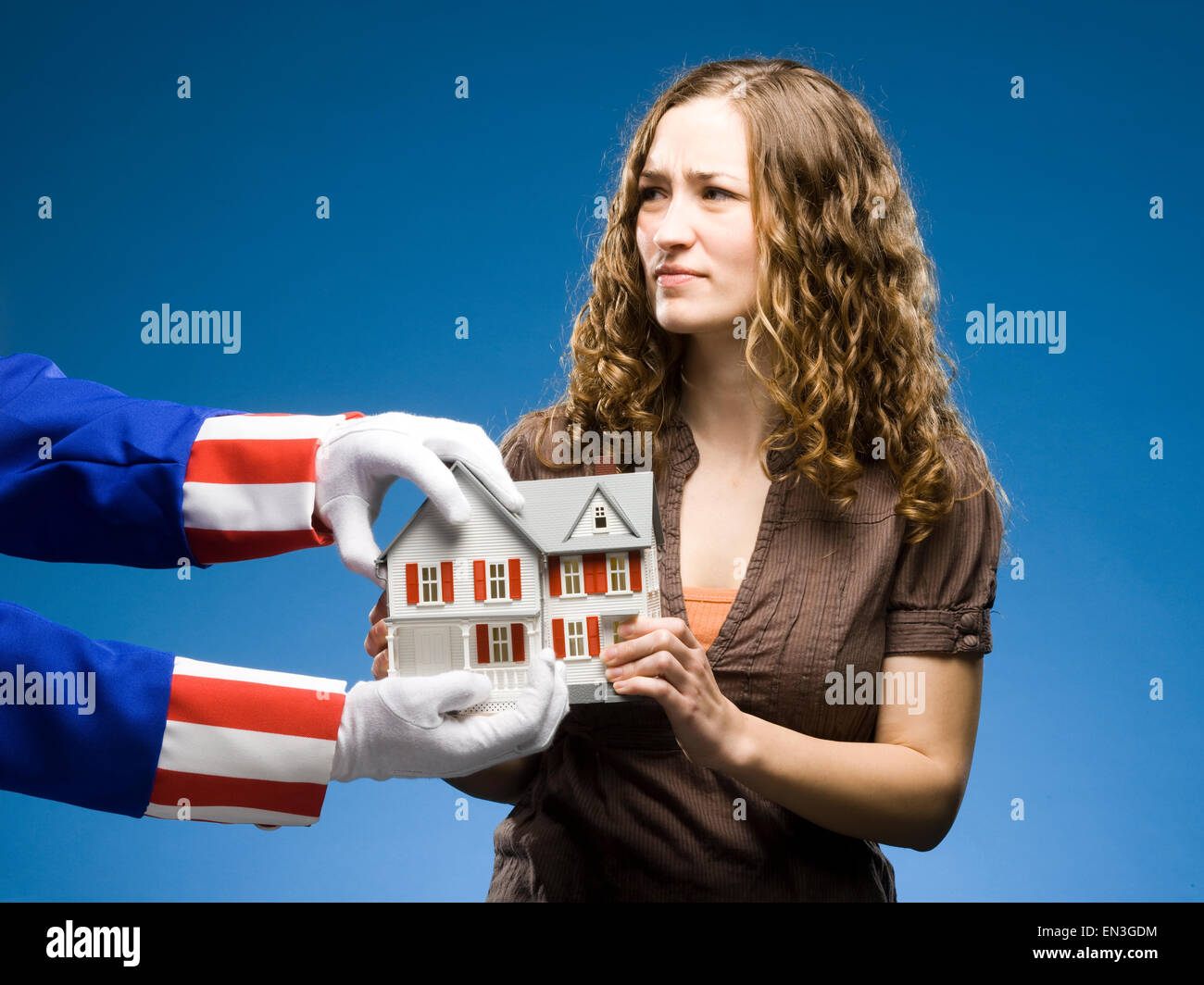 Femme tenant une miniature house alors que l'Oncle Sam tente de l'enlever Banque D'Images