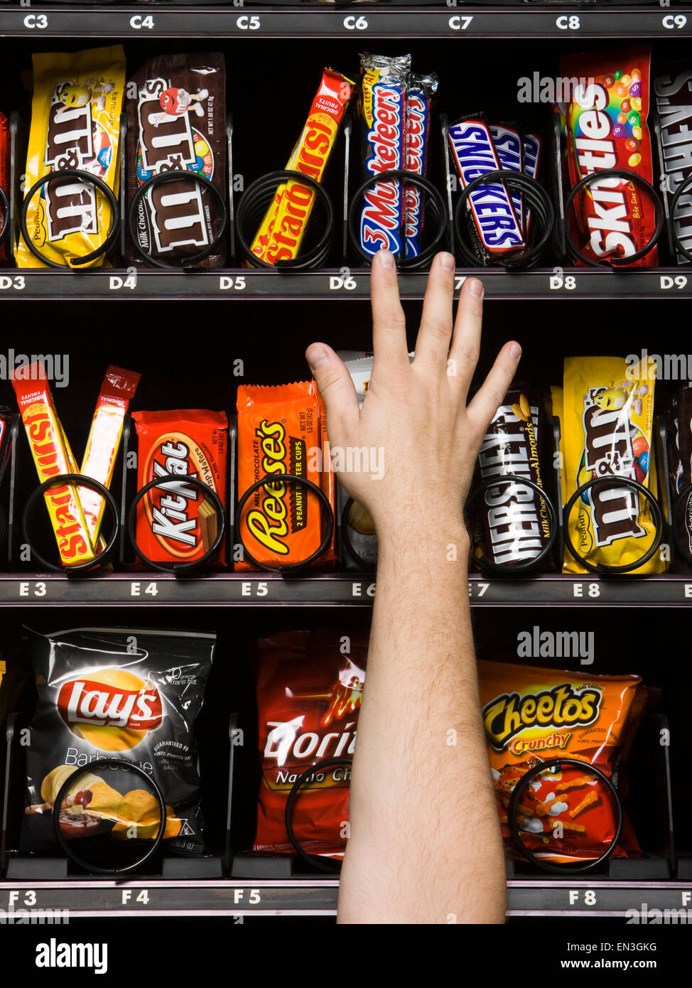 Hand Reaching for candy dans un distributeur automatique Banque D'Images