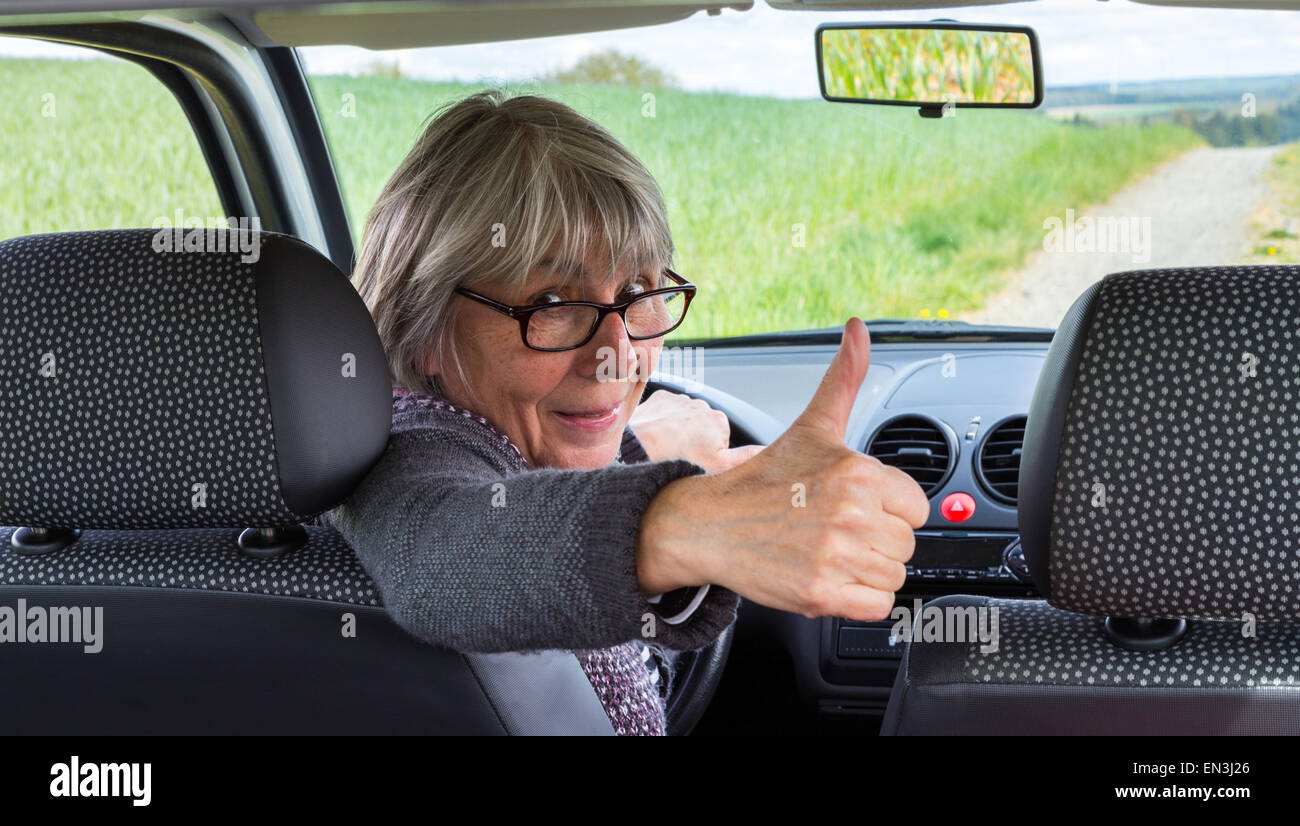 Senior Woman dans la voiture avec Thumbs up. Banque D'Images