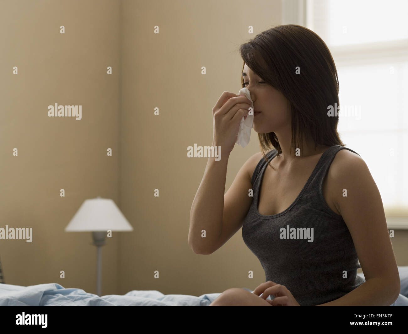 Femme assise sur le lit avec tissu à nez Banque D'Images