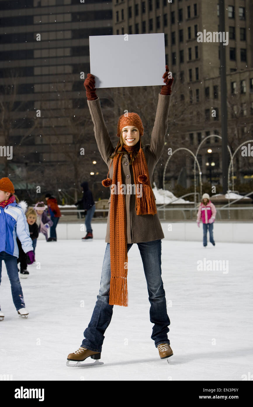 Woman holding blank sign avec les patins à l'extérieur en hiver Banque D'Images