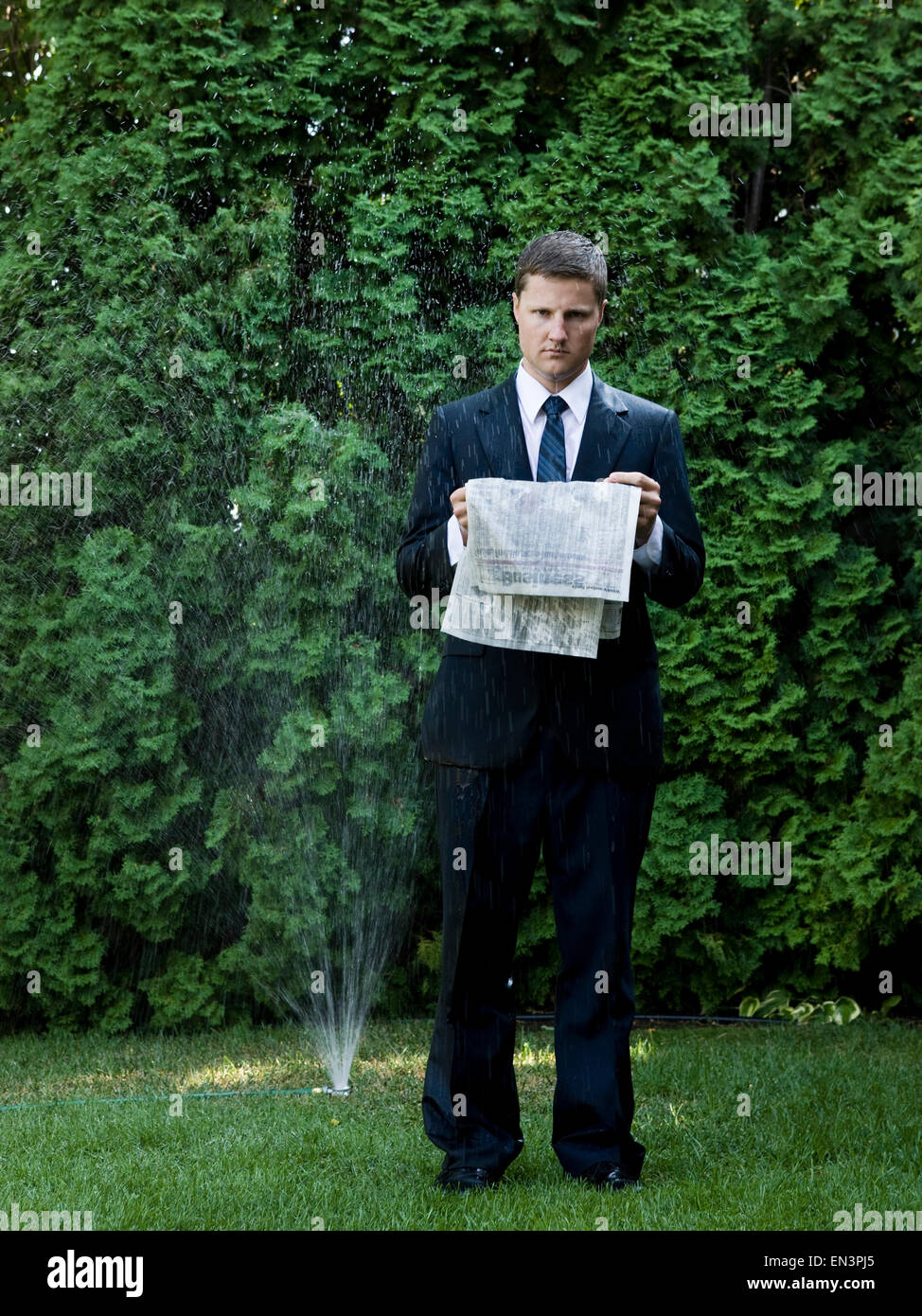 Homme en costume debout à côté d'un sprinkleur Banque D'Images