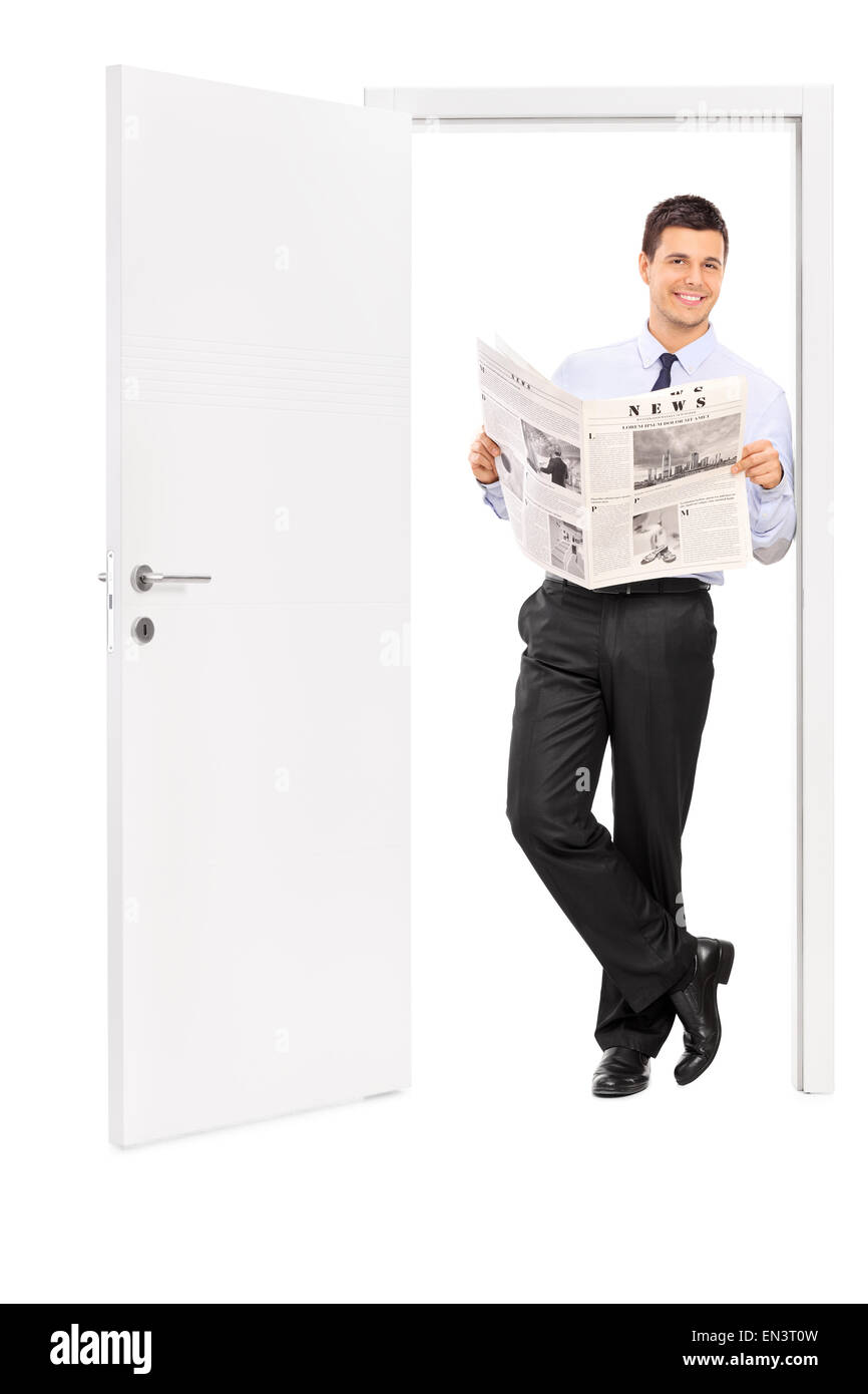 Portrait d'un jeune homme lisant un journal et s'appuyant sur le châssis d'une porte ouverte isolé sur fond blanc Banque D'Images