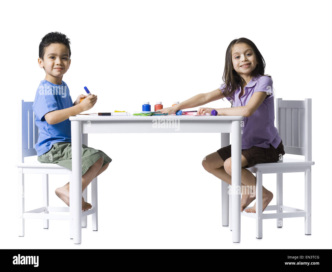 Boy and girl sitting at table faisant de l'artisanat Banque D'Images