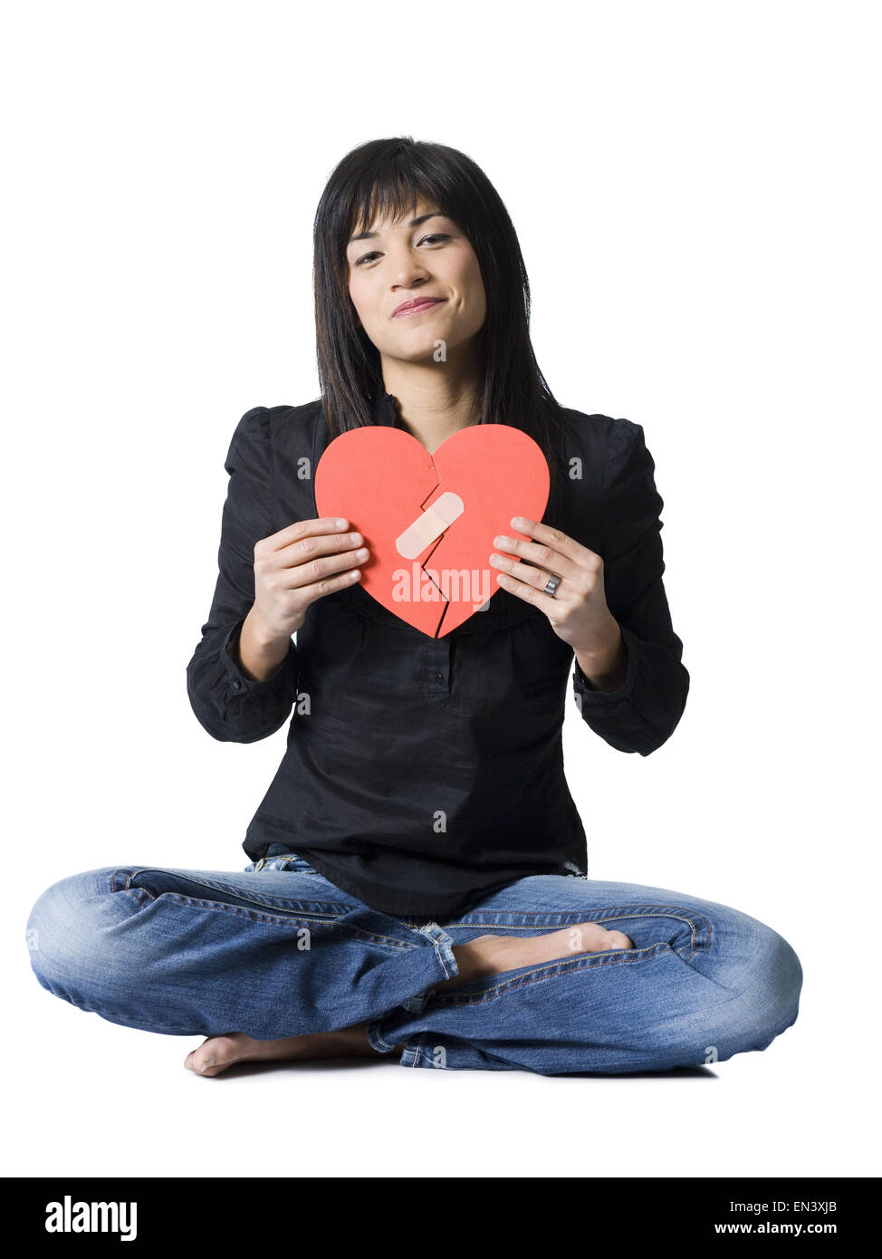 Woman sitting cross legged avec mandé red heart smiling Banque D'Images