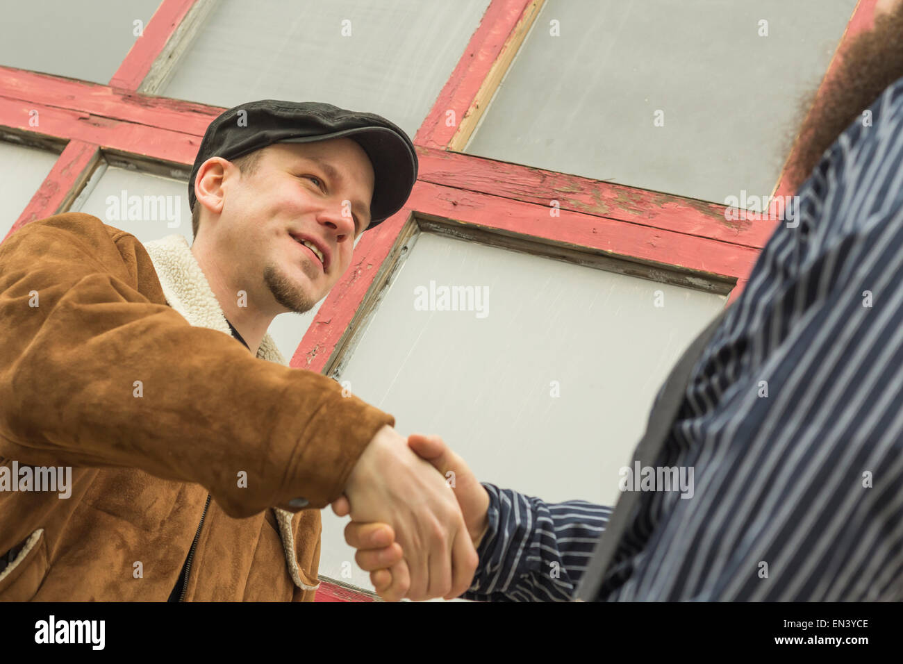 Deux amis bien habillé se serrer la main comme ils accueillent l'autre sur une rue de la ville Banque D'Images
