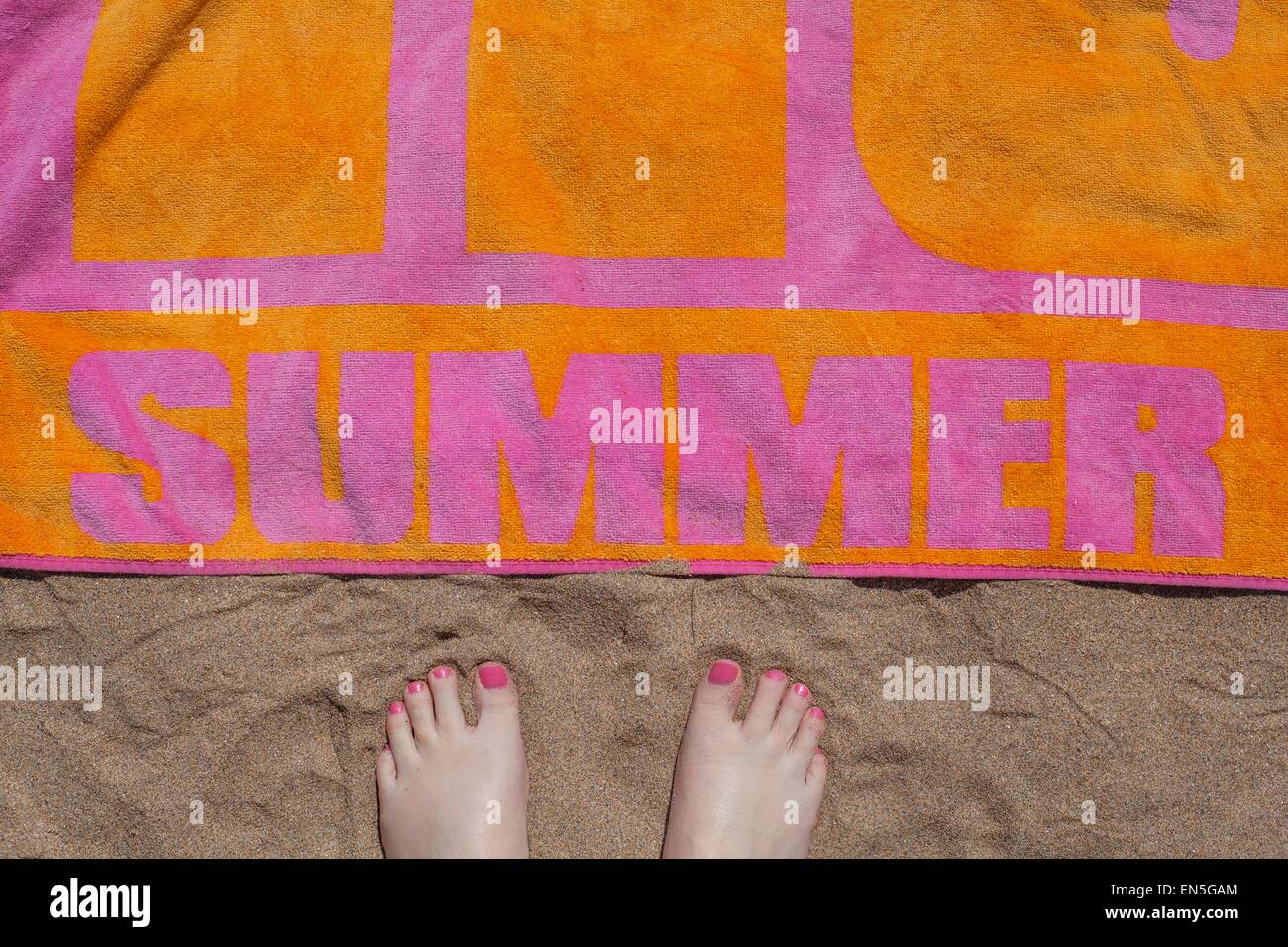 Vue de pieds pieds près d'une serviette de plage colorée sur le sable Banque D'Images