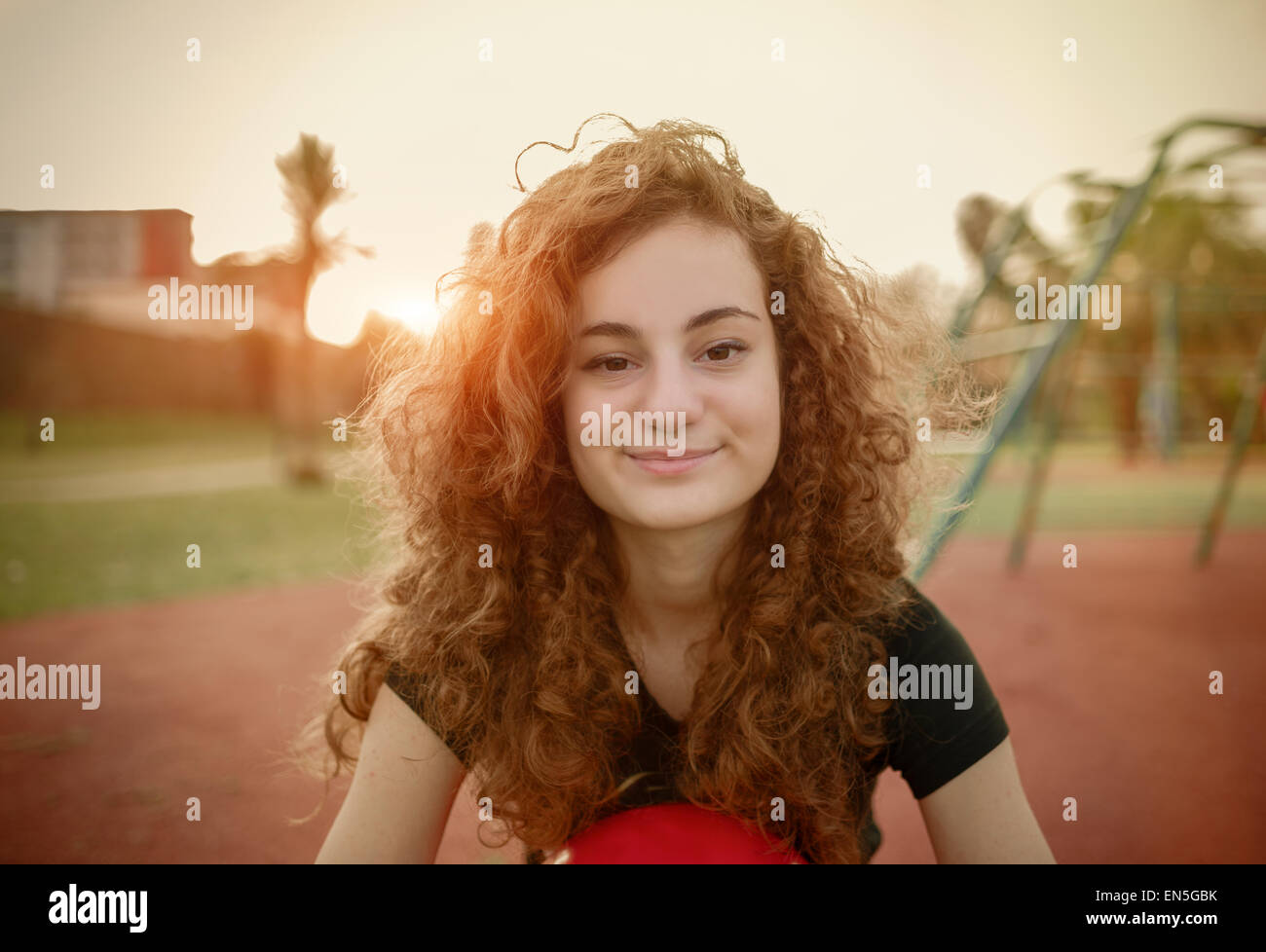 Jeune fille aux cheveux bouclés qui posent dans le coucher du soleil - image filtrée Banque D'Images