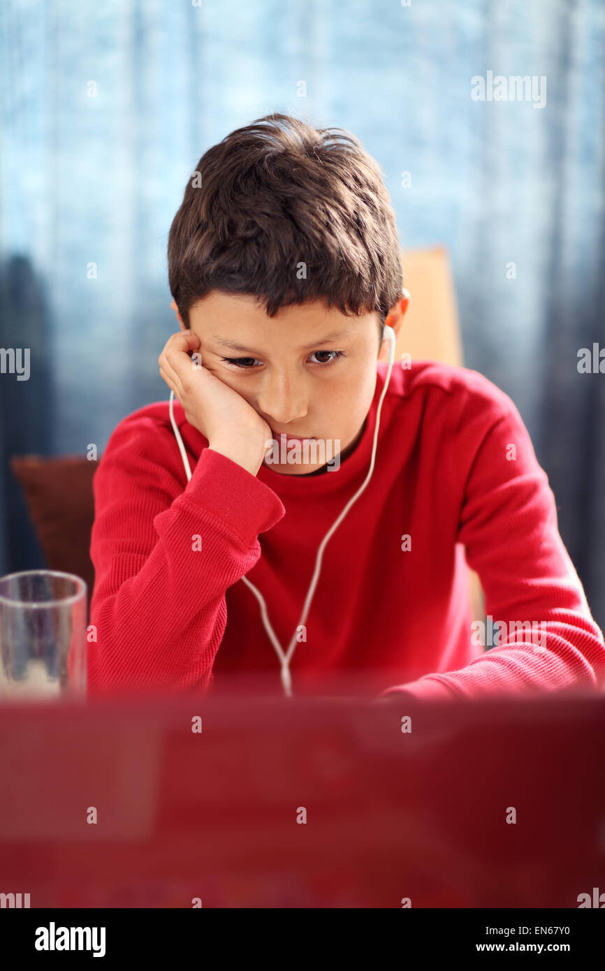 Ennuyer jeune garçon fait ses devoirs sur un ordinateur - avec une faible profondeur de champ Banque D'Images