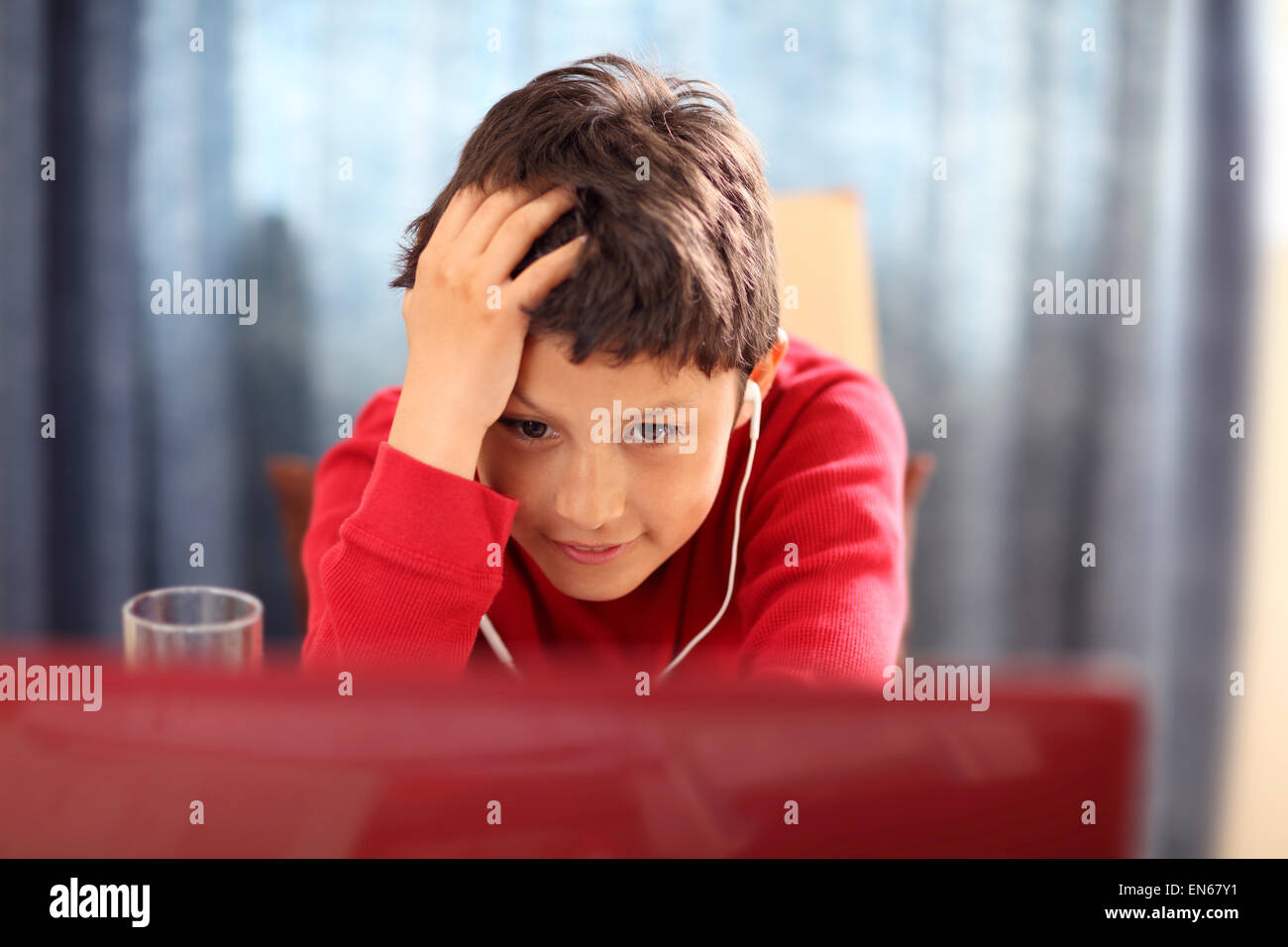 Jeune garçon fait ses devoirs sur un ordinateur - avec une faible profondeur de champ Banque D'Images