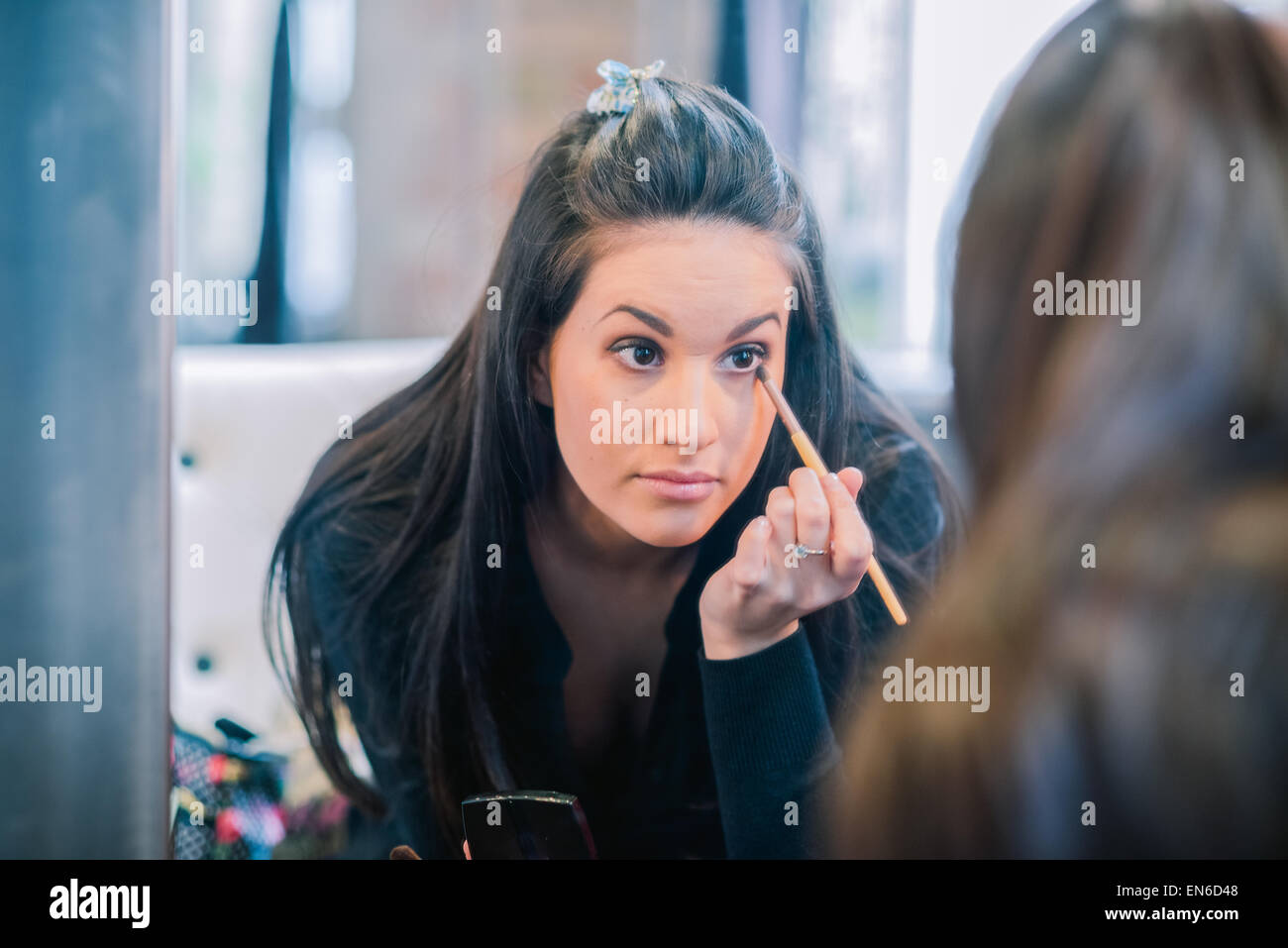 Attractive brunette woman applying eye shadow comme vu dans le miroir Banque D'Images