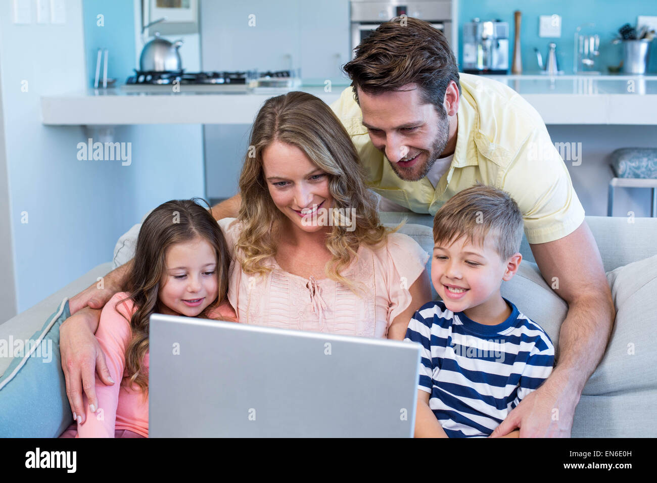 Famille heureuse sur le canapé à l'aide d'ordinateur portable Banque D'Images
