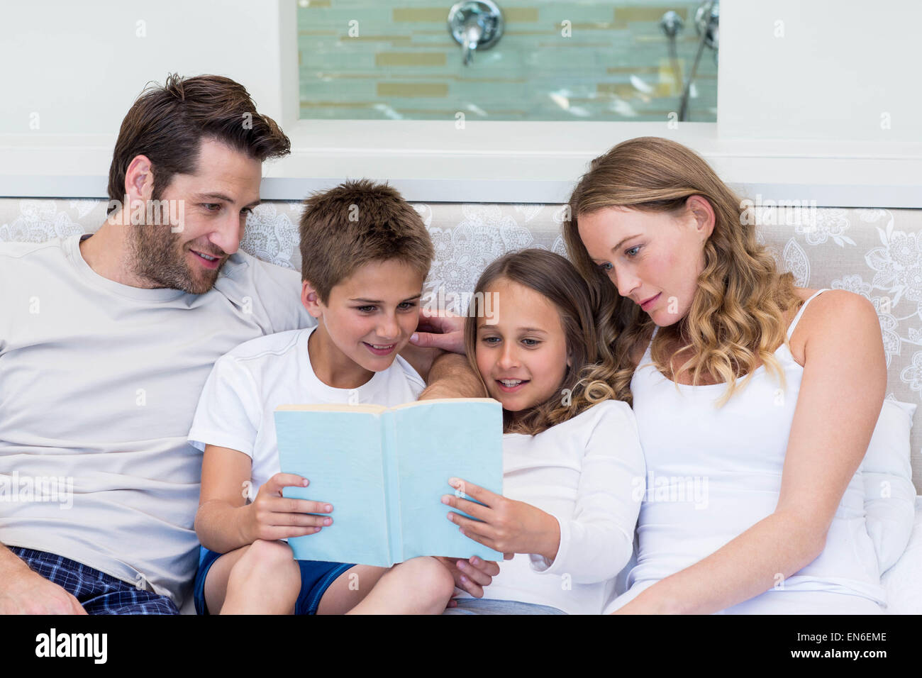 Famille heureuse sur le bed reading book Banque D'Images
