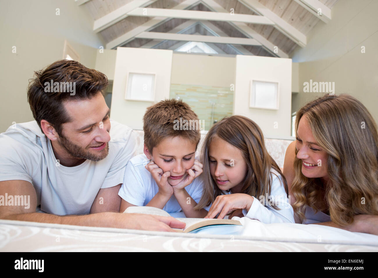Famille heureuse sur le bed reading book Banque D'Images