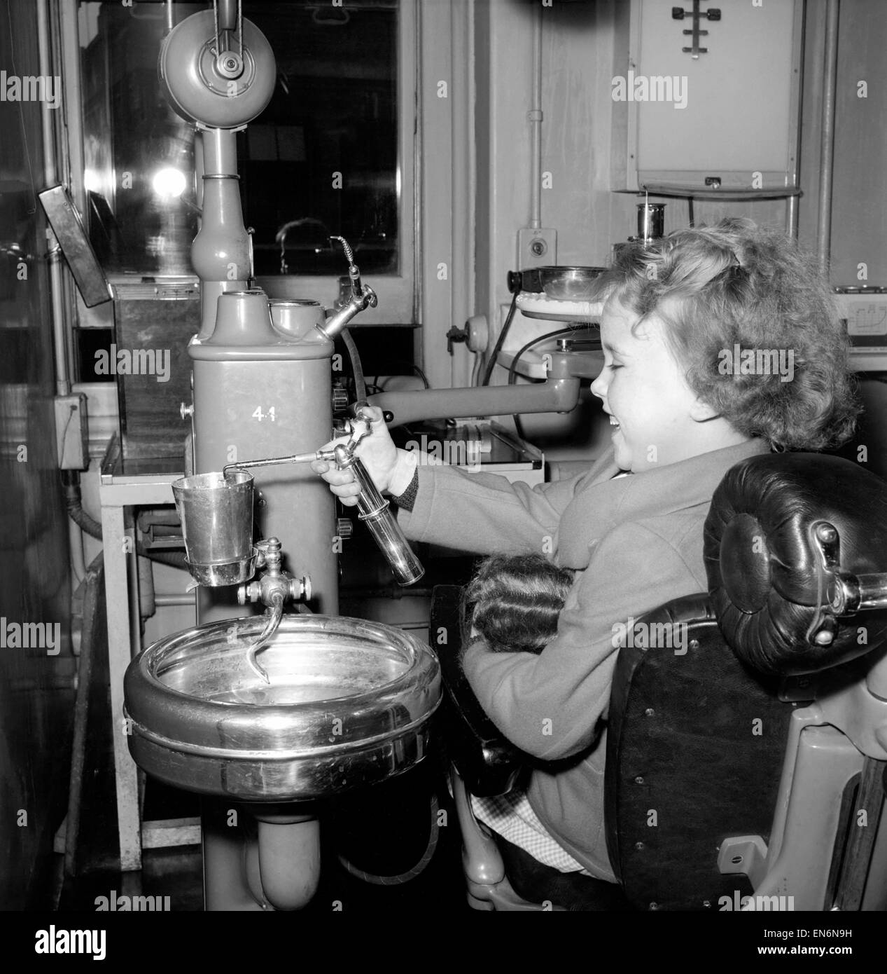 Fille dans le fauteuil du dentiste à une clinique dentaire pour les enfants. 1954. Banque D'Images