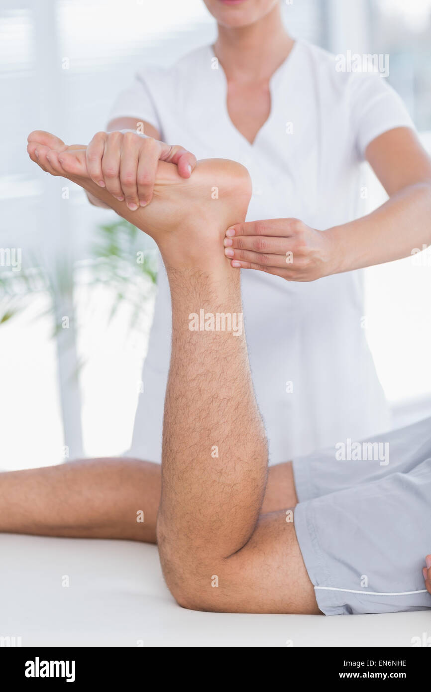 Physiothérapeute massage des jambes à faire son patient Banque D'Images