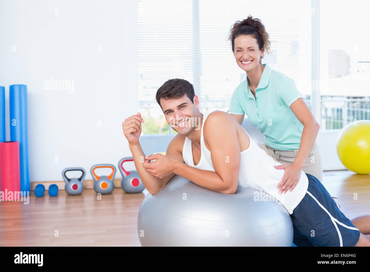 Trainer helping man with exercise ball Banque D'Images