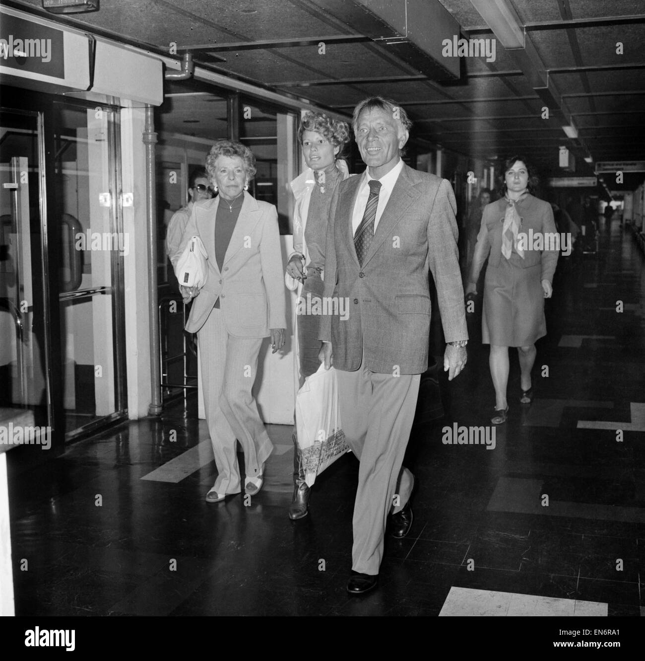 Richard Burton et sa femme Susie Quitter Heathrow pour leur accueil à Genève. Il a vite emprunté de lunettes à partir d'une vieille amie Valeria Douglas, - dire que le soleil était trop lumineux, dans le couloir de la salle d'embarquement. Juillet 1978 Banque D'Images