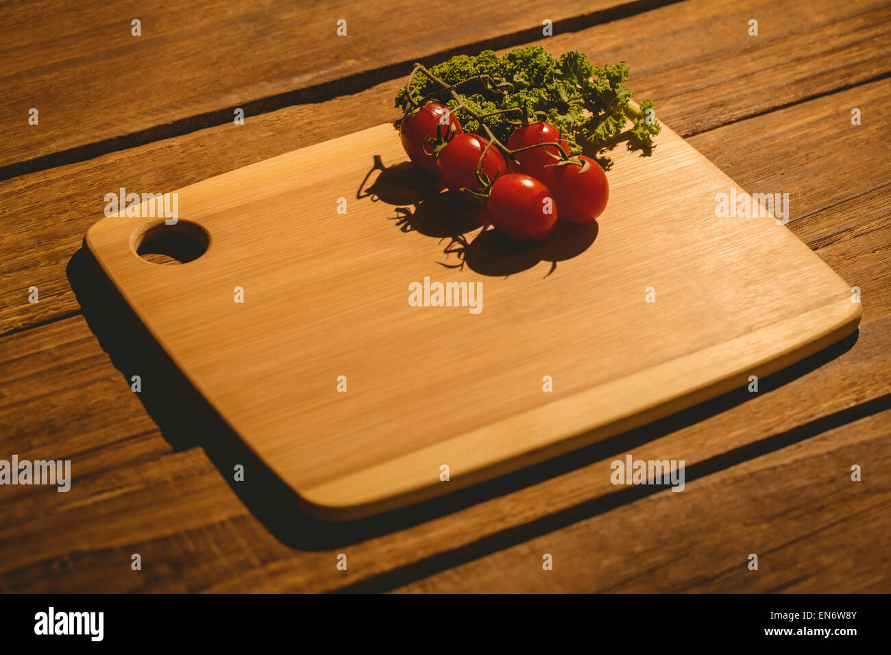 Les tomates cerise et le persil sur planche à découper Banque D'Images