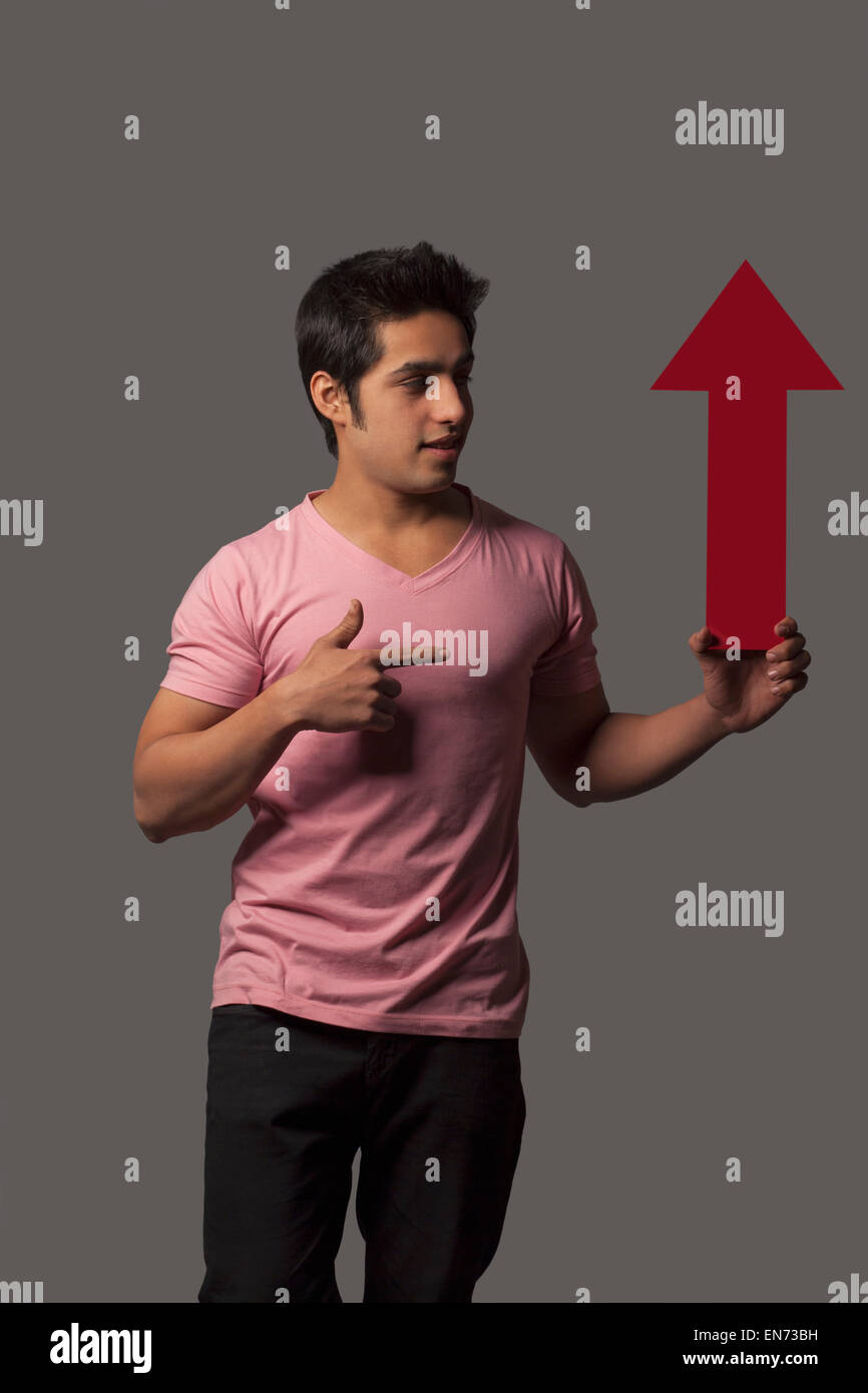 Jeune homme gesticulant à arrow sign Banque D'Images