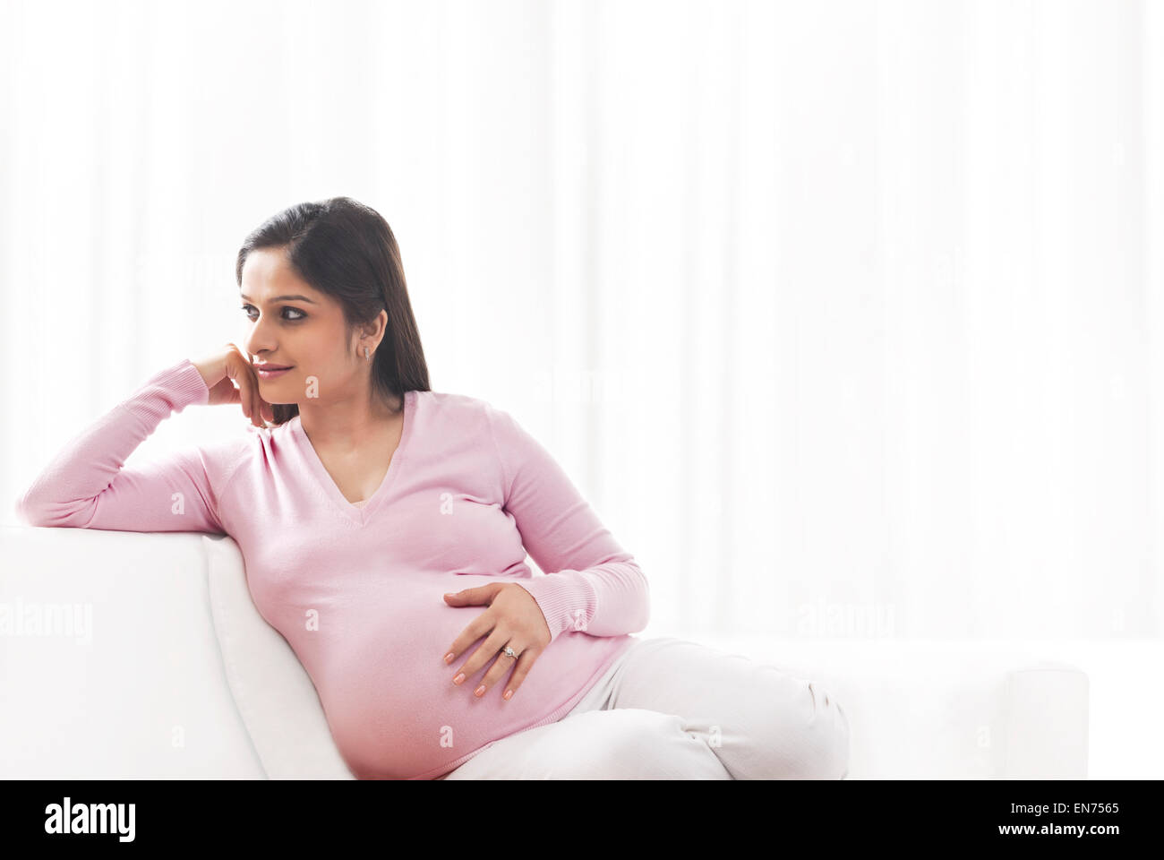 Pregnant woman sitting on a couch Banque D'Images