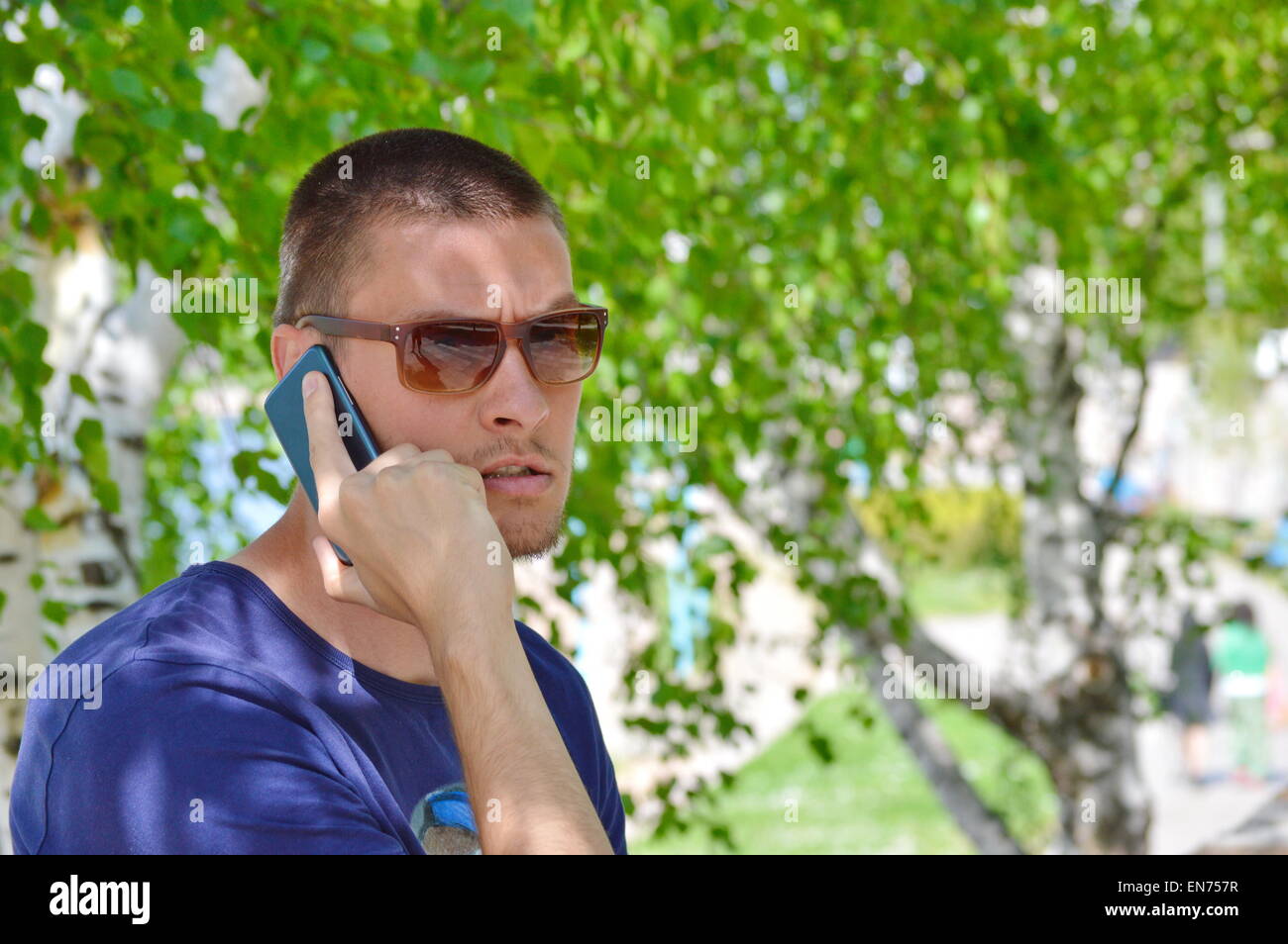Garçon en colère au téléphone dans un parc Banque D'Images