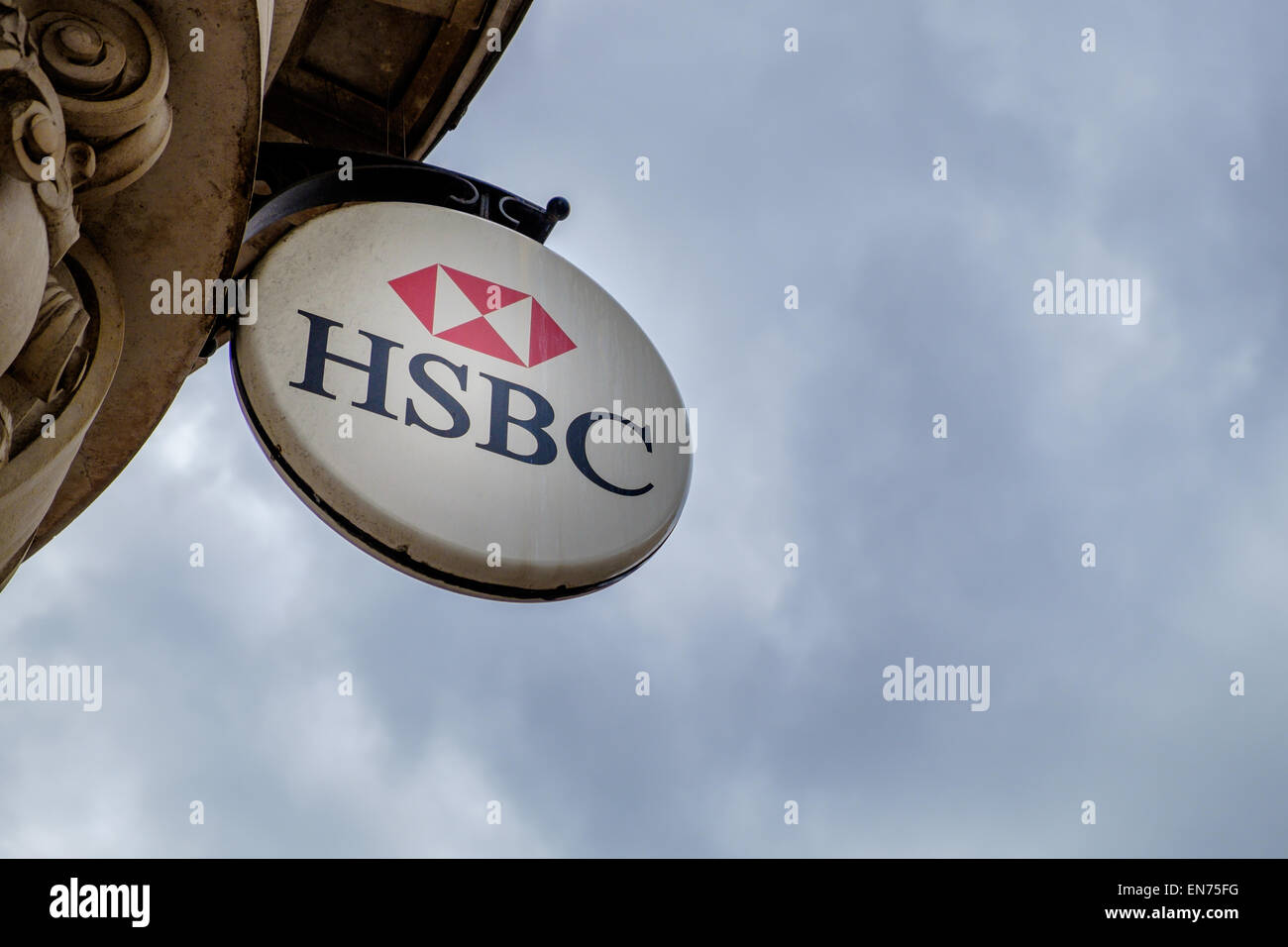 Un signe au-dessus de la HSBC Cirencester succursale principale de la Banque mondiale, tourné contre un sombre, ciel nuageux prévisions de l'économie concept conceptuel Banque D'Images