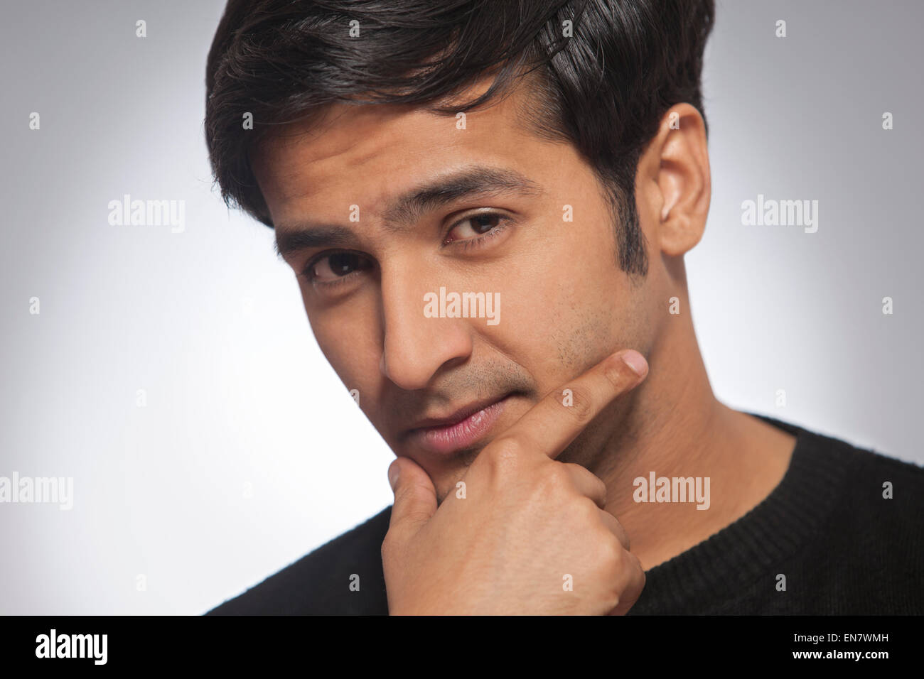 Close up portrait of young man with hand on chin Banque D'Images