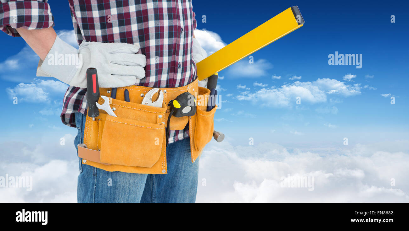 Image composite de réparateur wearing tool belt en position debout avec les mains sur les hanches Banque D'Images