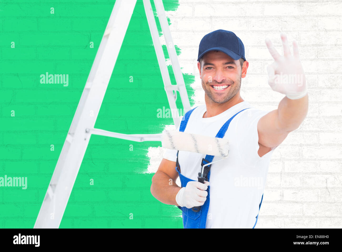 Libre de handyman with paint roller gesturing okay Banque D'Images