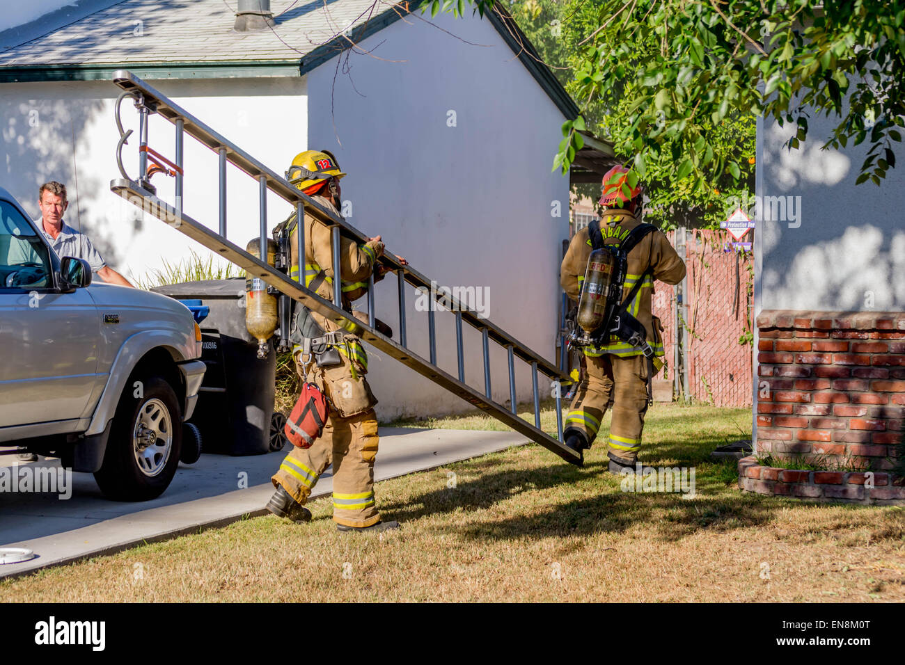 Burbank pompiers de l'incendie d'une maison portant une échelle. Banque D'Images