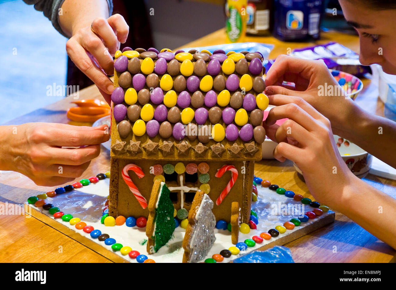 Vue horizontale d'un Gingerbread House sont décorées par une mère et sa fille pour Noël. Banque D'Images