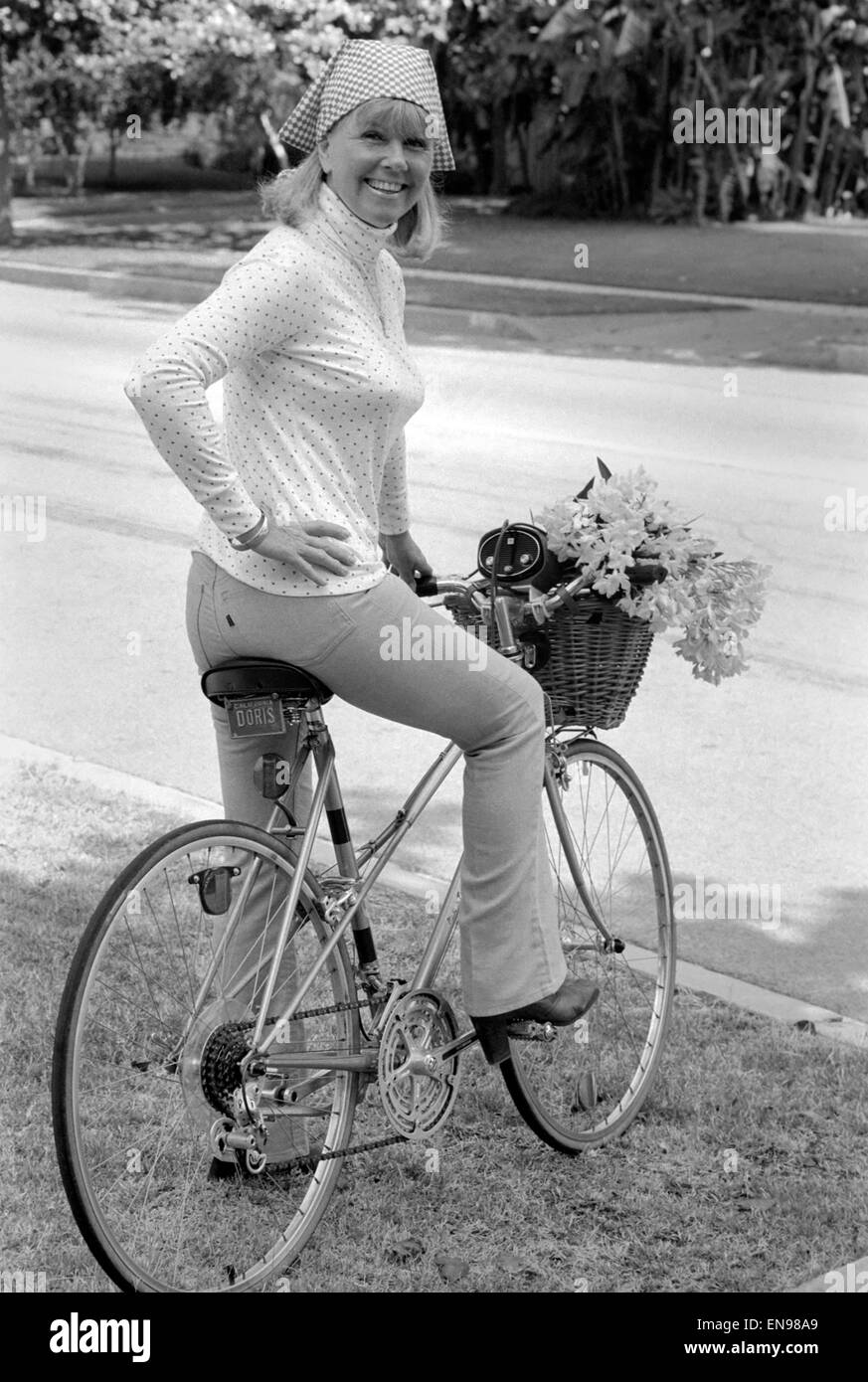 Doris Day vu tenant un bouquet de fleurs sur sa bicyclette, elle roule tous les jours pour garder la forme. 26 août 1980. Banque D'Images