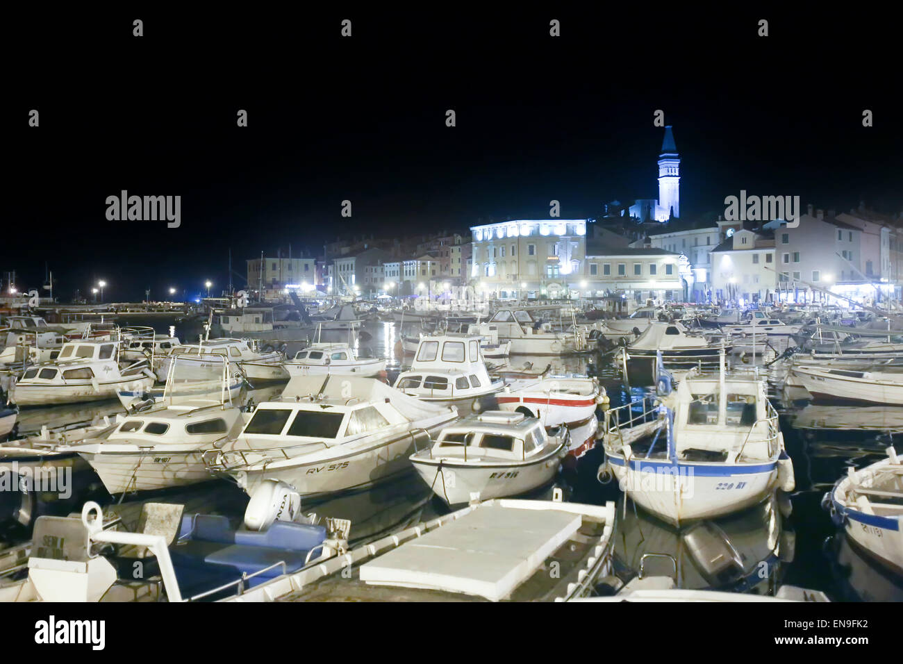 Un grand groupe de bateaux ancrés dans la marina avec une vue de la ville au bord de mer nuit à Rovinj, Croatie. Banque D'Images