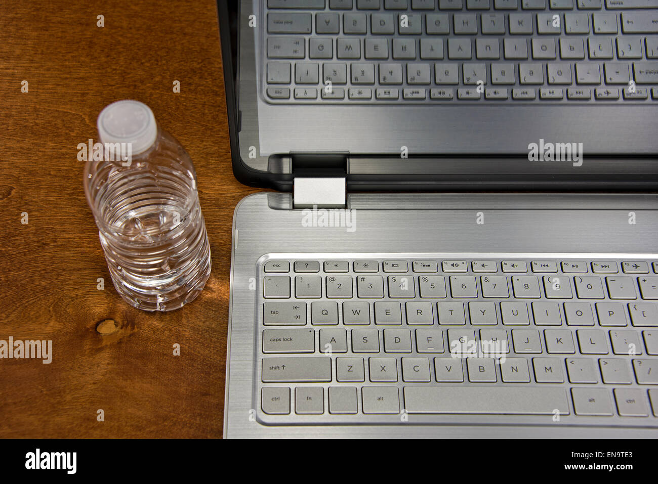 Bouteille d'eau en plastique et d'un ordinateur portable sur un bureau en bois. Banque D'Images