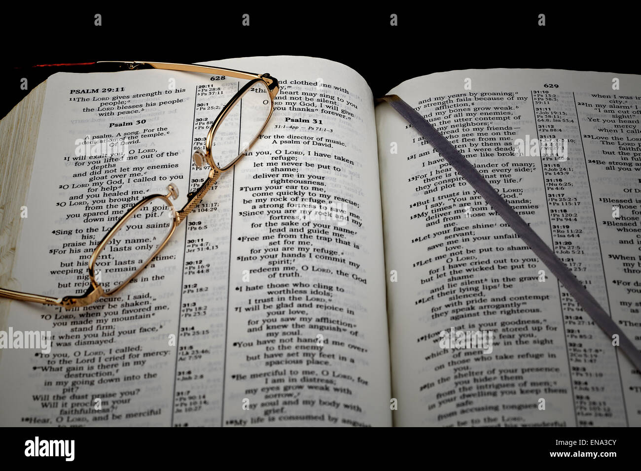 L'étude de la Bible psaume 30 dans la lumière du soir avec des lunettes de lecture sur fond noir Banque D'Images