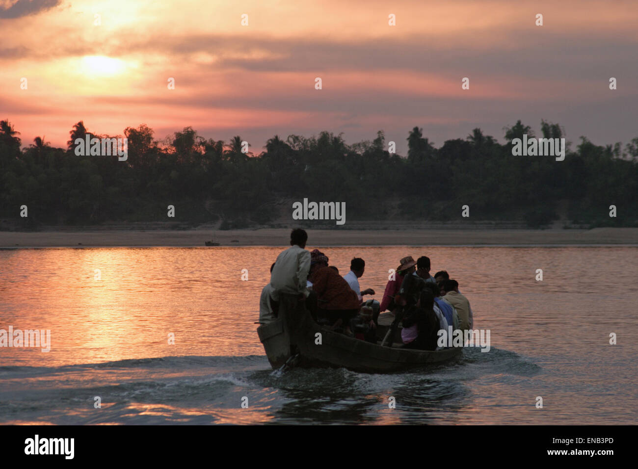 Les gens traversent le fleuve Mékong dans un vieux bateau en bois comme le coucher du soleil arrive à Kratie, au Cambodge. Banque D'Images
