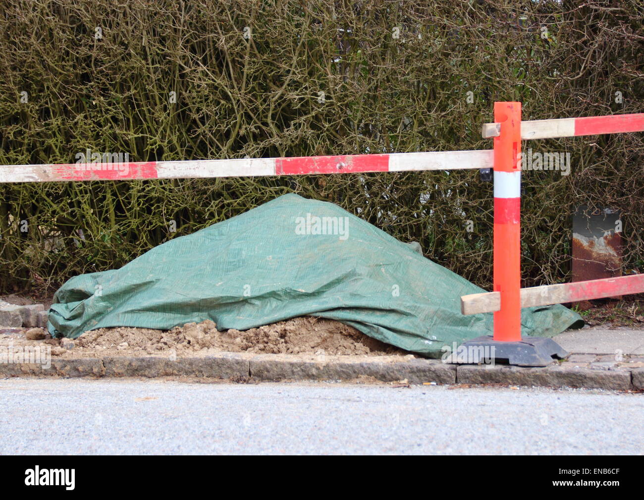 Travaux routiers palissade avec couverts en plastique tas de terre Banque D'Images