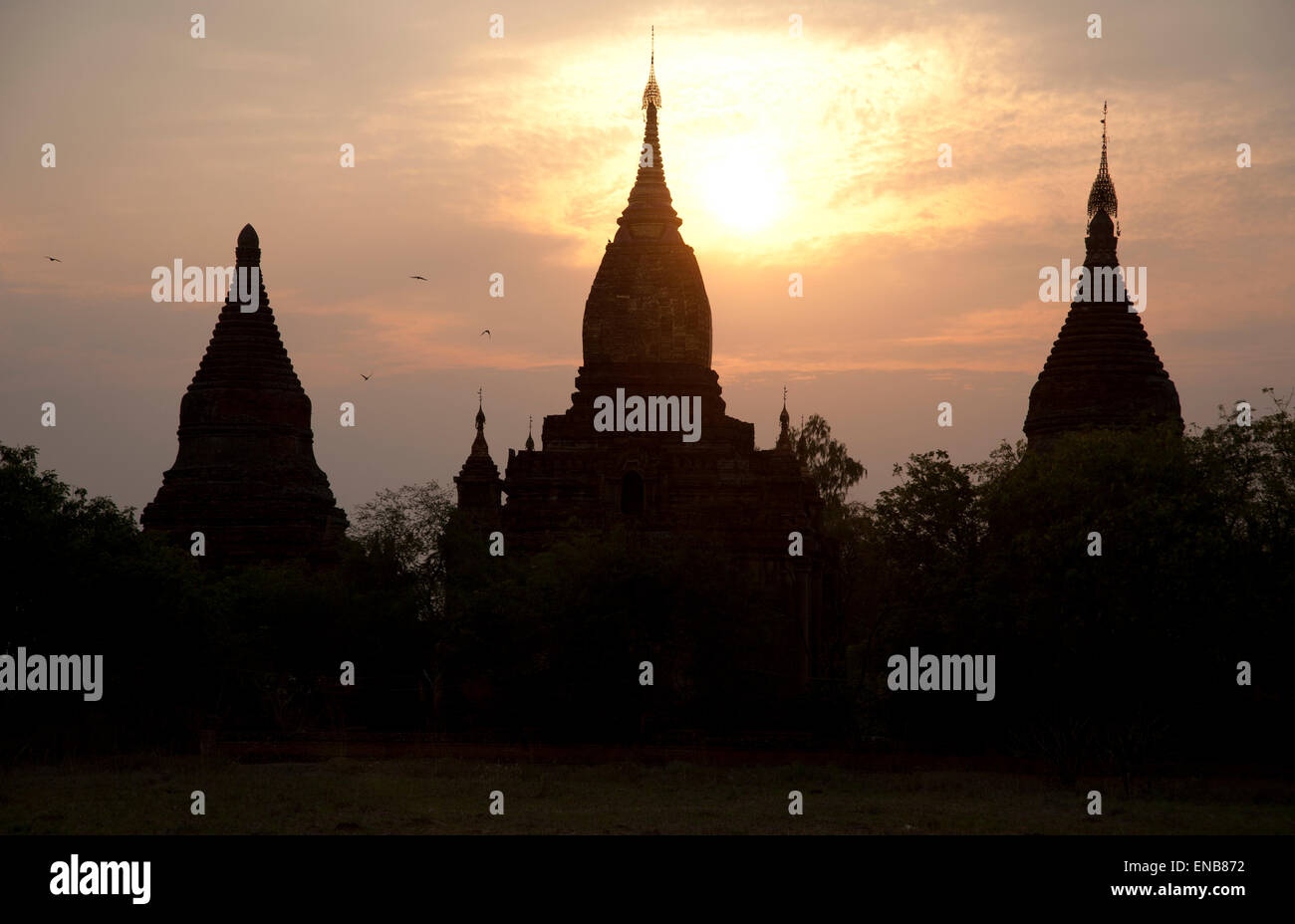 Trois silhouettes sombres des flèches contre le temple d'or d'un coucher de Bagan Myanmar Banque D'Images