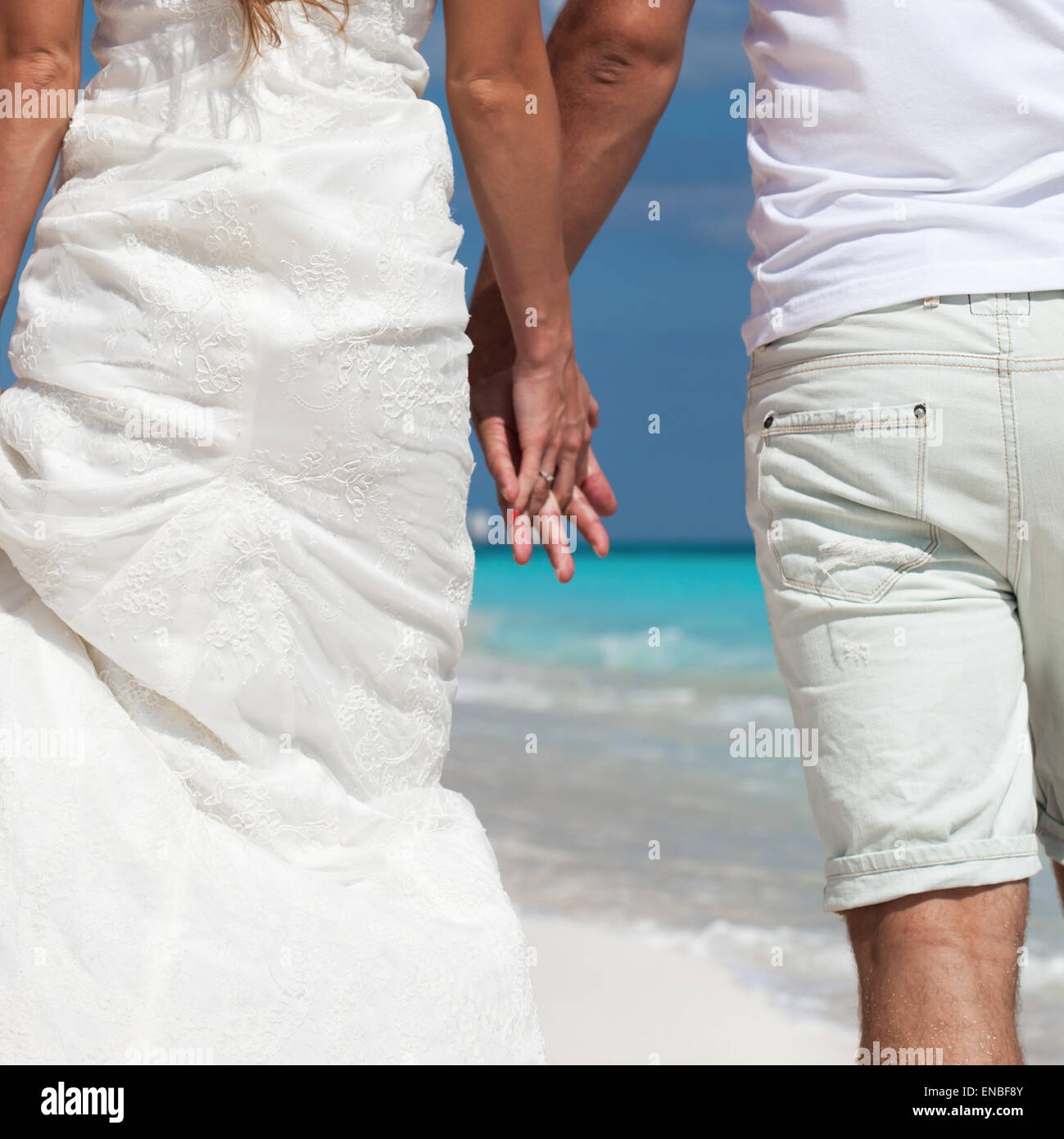 Jeunes et belles jeunes mariés amoureux se tenant la main et de s'éloigner de la médecine tropicale et plage de sable, vue arrière Banque D'Images