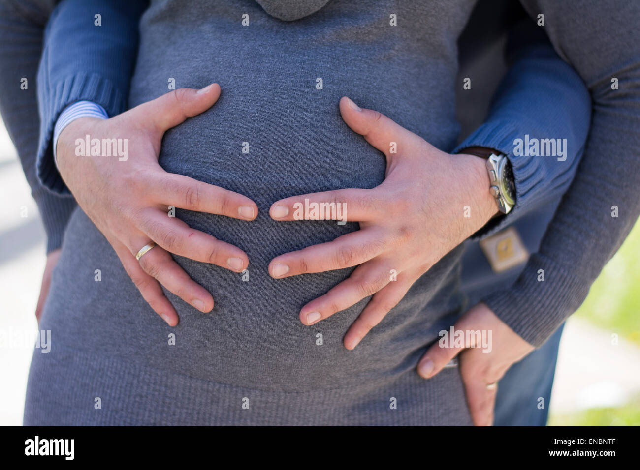 Les mains des hommes de toucher le ventre de la femme enceinte en chandail gris Banque D'Images