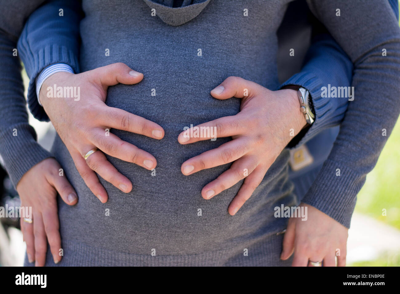 Les mains des hommes de toucher le ventre de la femme enceinte en chandail gris Banque D'Images