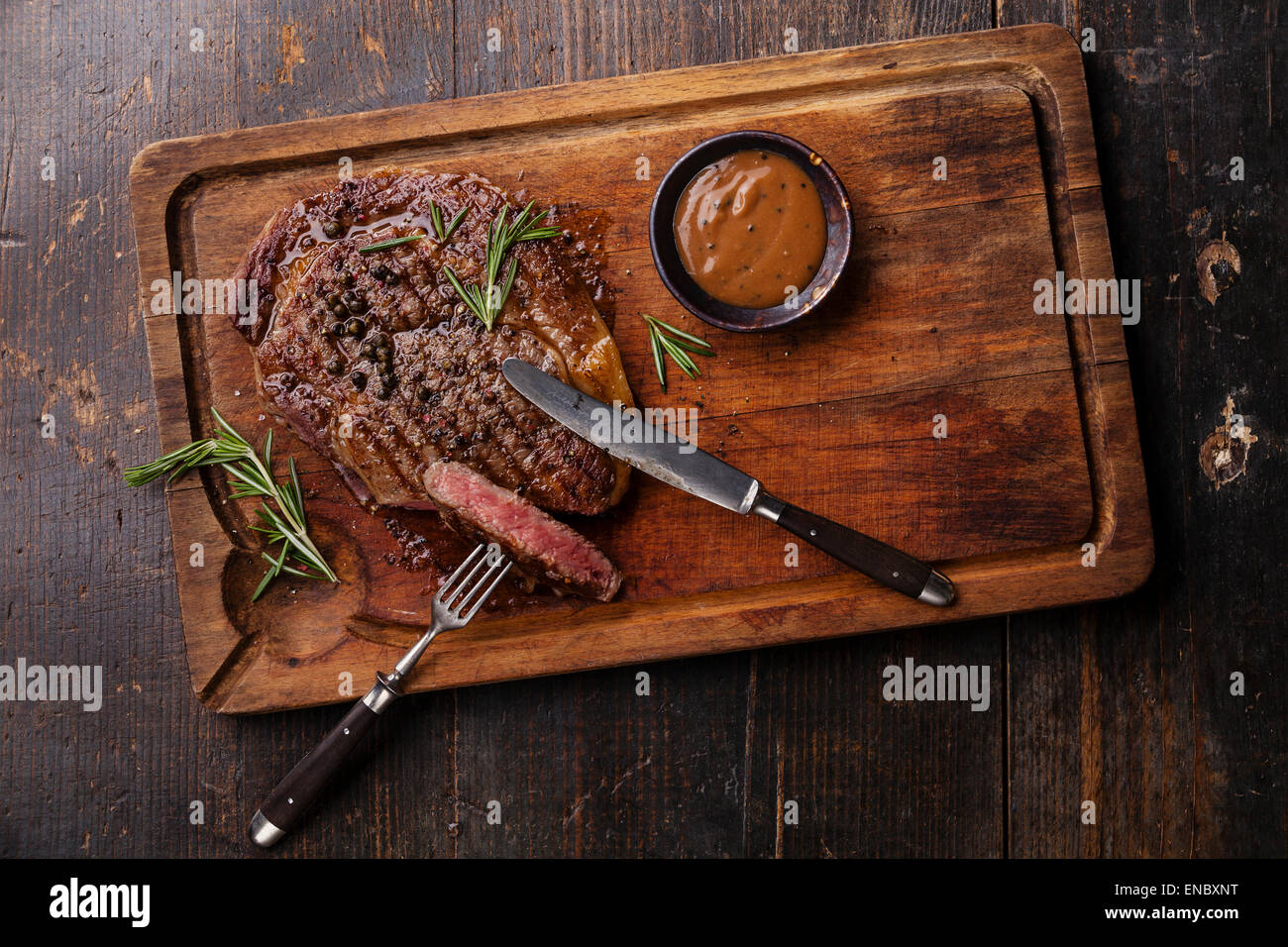Black Angus Steak grillé sauce au poivre et du faux-filet sur la viande à découper sur fond de bois foncé Banque D'Images