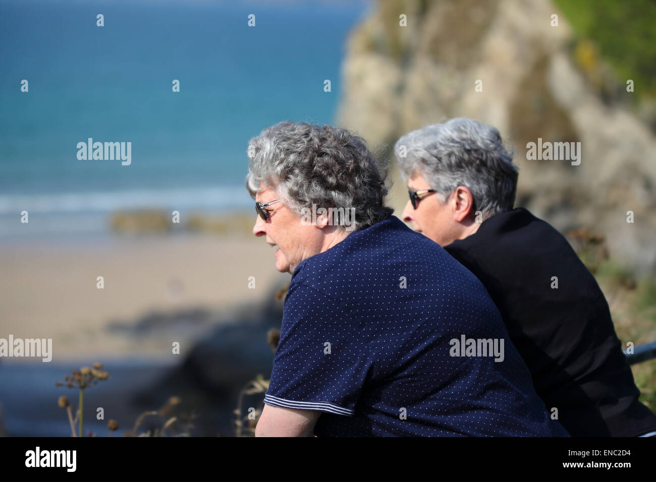 Deux sœurs jumelles âgées donnent sur l'océan dans l'été Banque D'Images