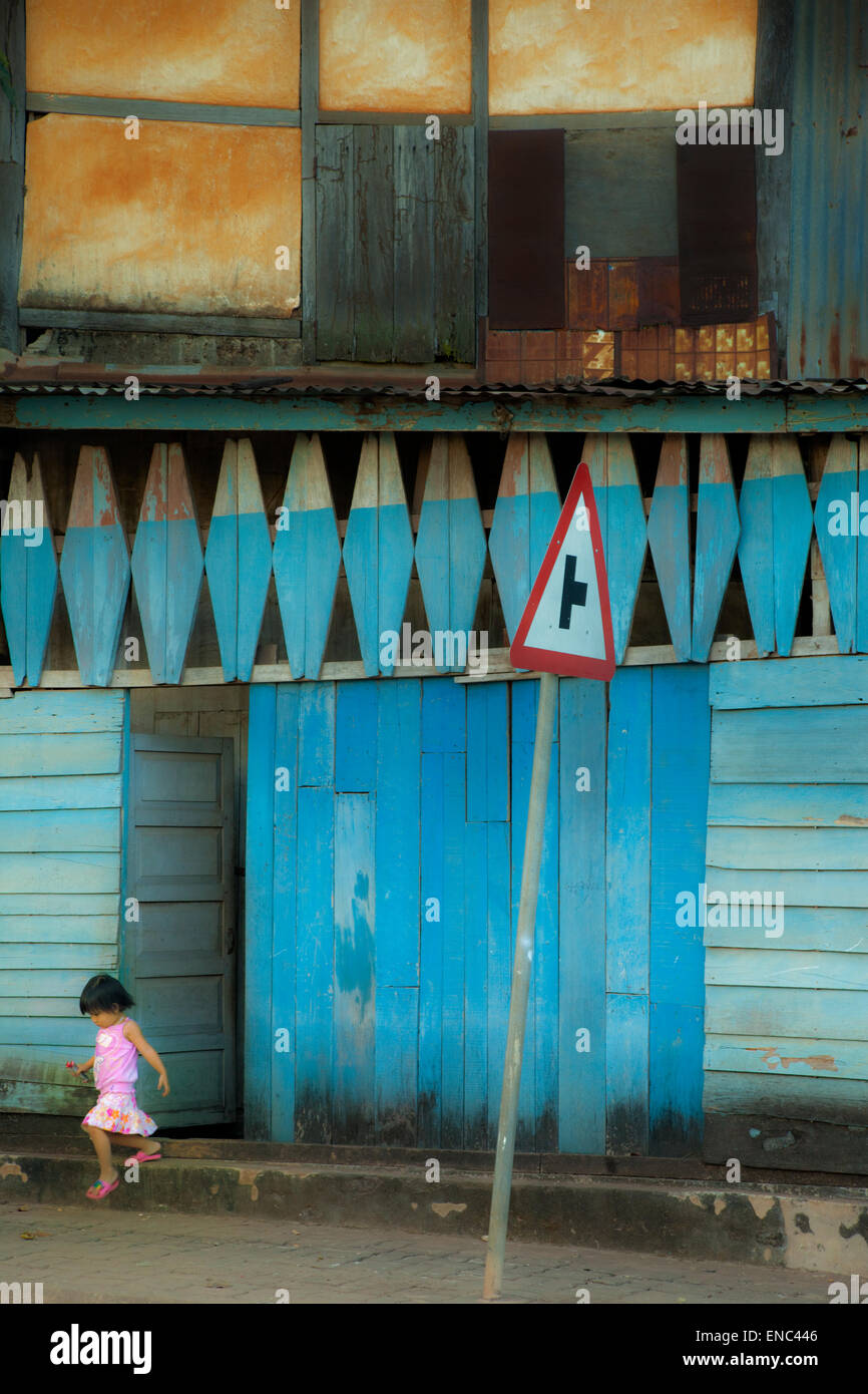 Une petite fille sort d'une porte dans une rue à Vientiane, Laos Banque D'Images