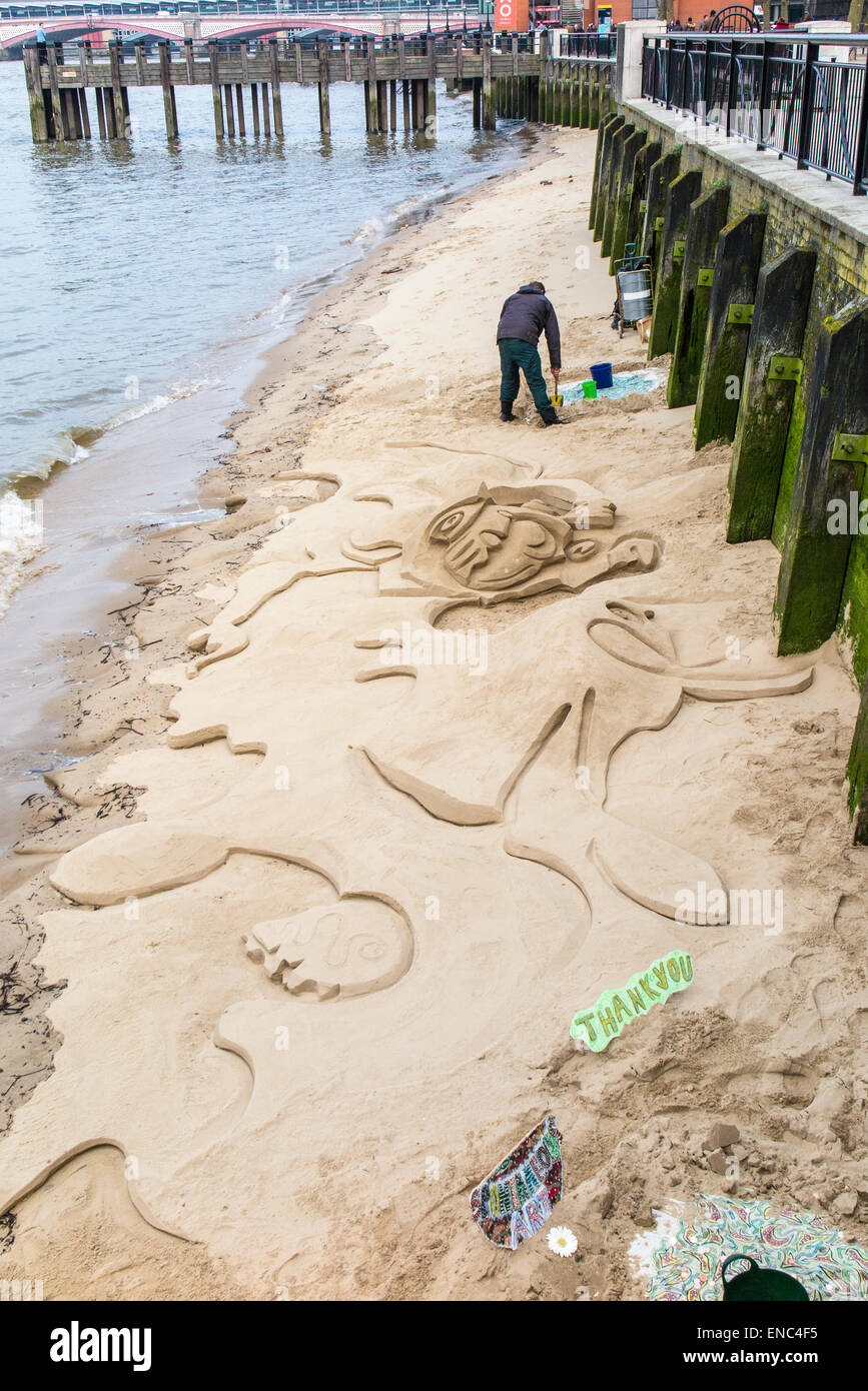 Sculpteur de sable dans le sable des chiffres sur un banc de sable à côté de la rivière à marée basse pour des conseils, sur la rive sud, Tamise, Londres SE1 Banque D'Images